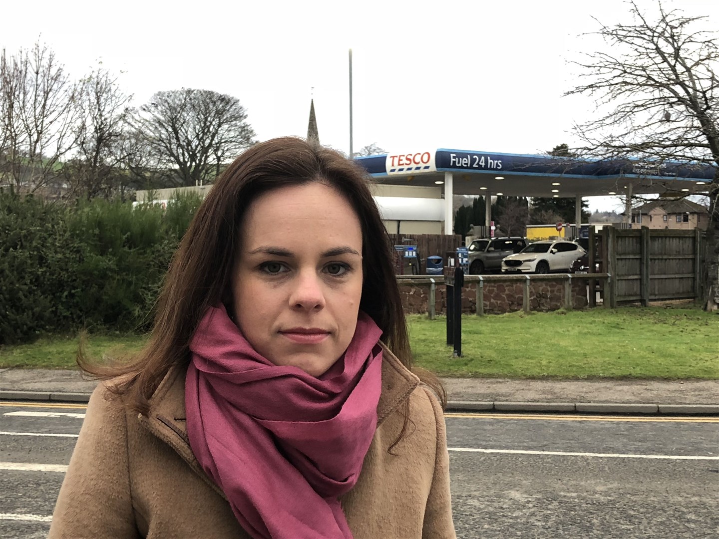 Kate Forbes outside Tesco filling station in Dingwall that advertises 24 hours fuel.