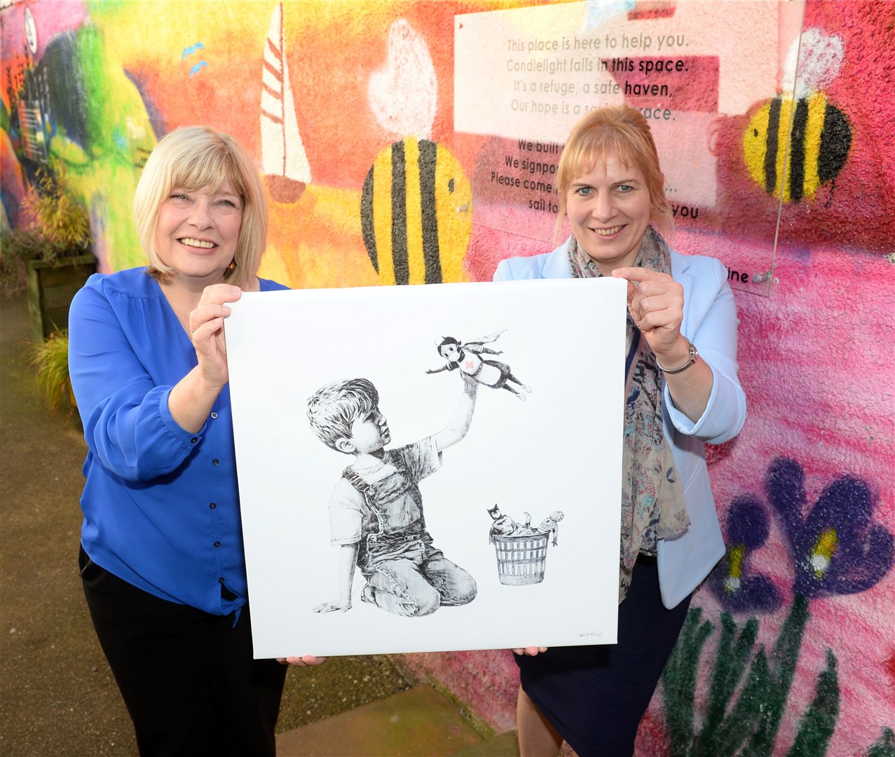 Bonnie McColl and Emilly Stokes of the Hive with a limited edition print of a Banksy artwork the 'Game changer' which is to be the prize for an NHS Highland superhero..Picture: Gary Anthony..