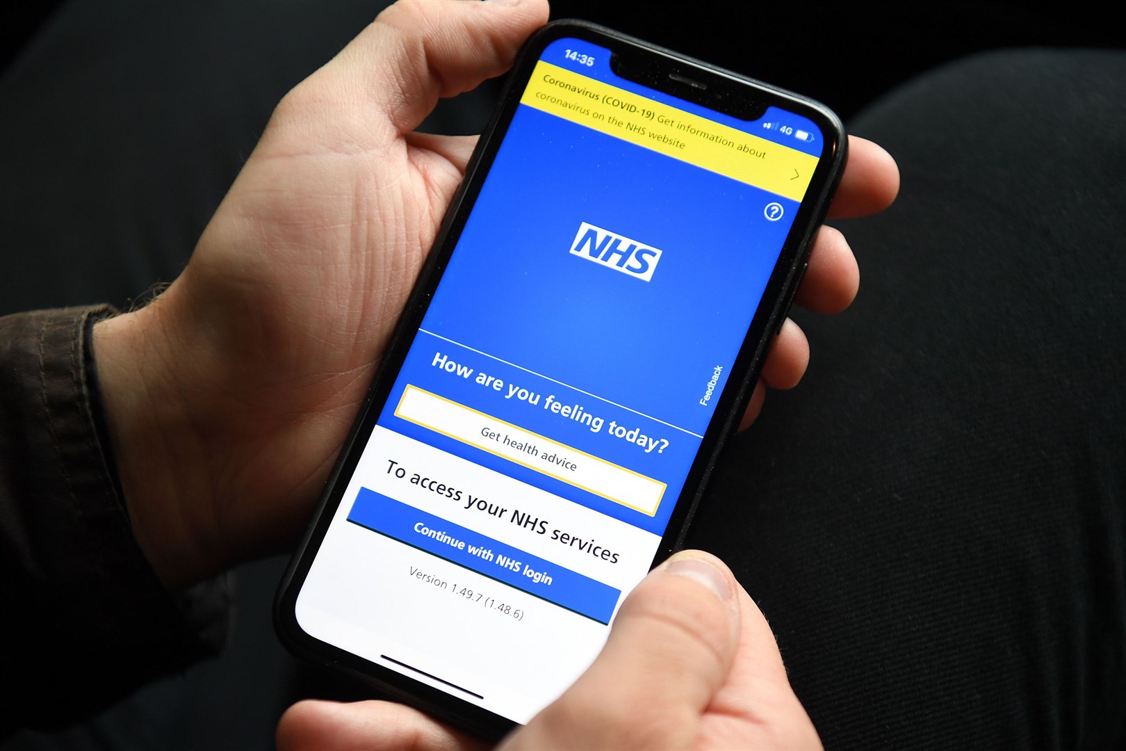 A person holding a mobile phone displaying the NHS app (Kirsty O’Connor/PA)
