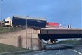 Lorry left hanging above A road after crashing into bridge barrier