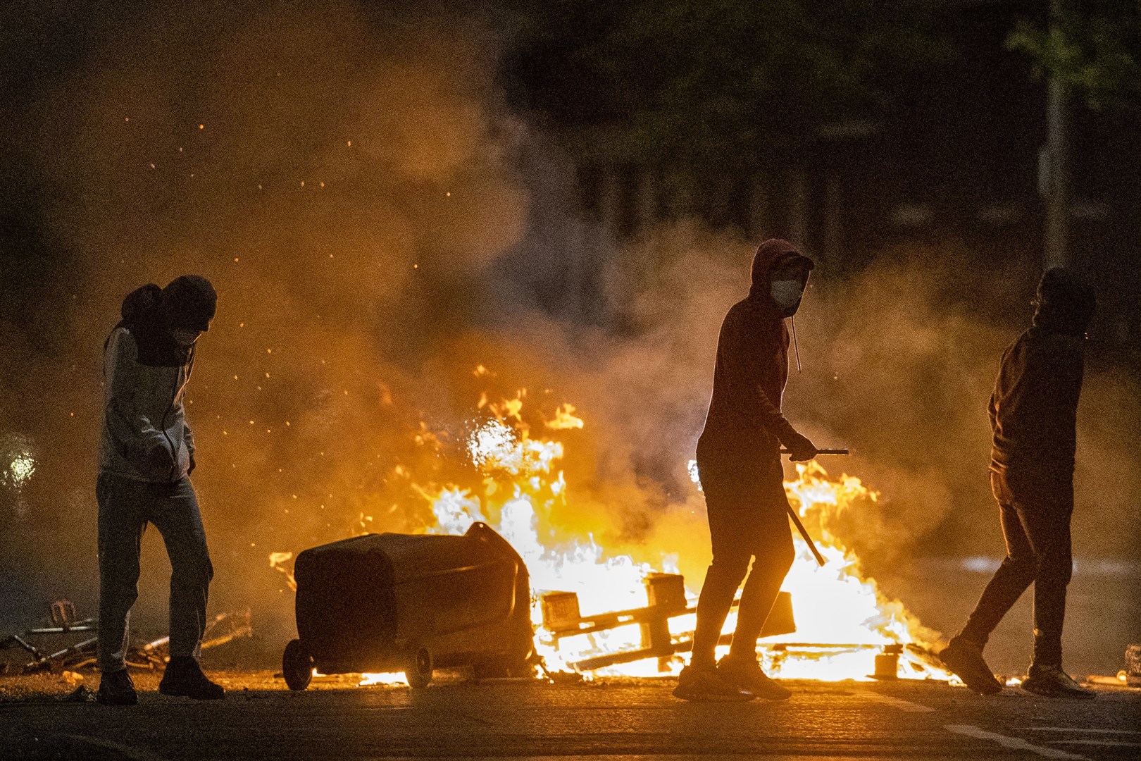 People stand next to a fire in a Belfast street during unrest (Liam McBurney/PA)