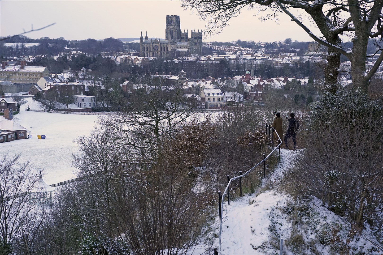 People take pictures from Pelaw Wood of a snow-covered Durham Cathedral (Owen Humphreys/PA)