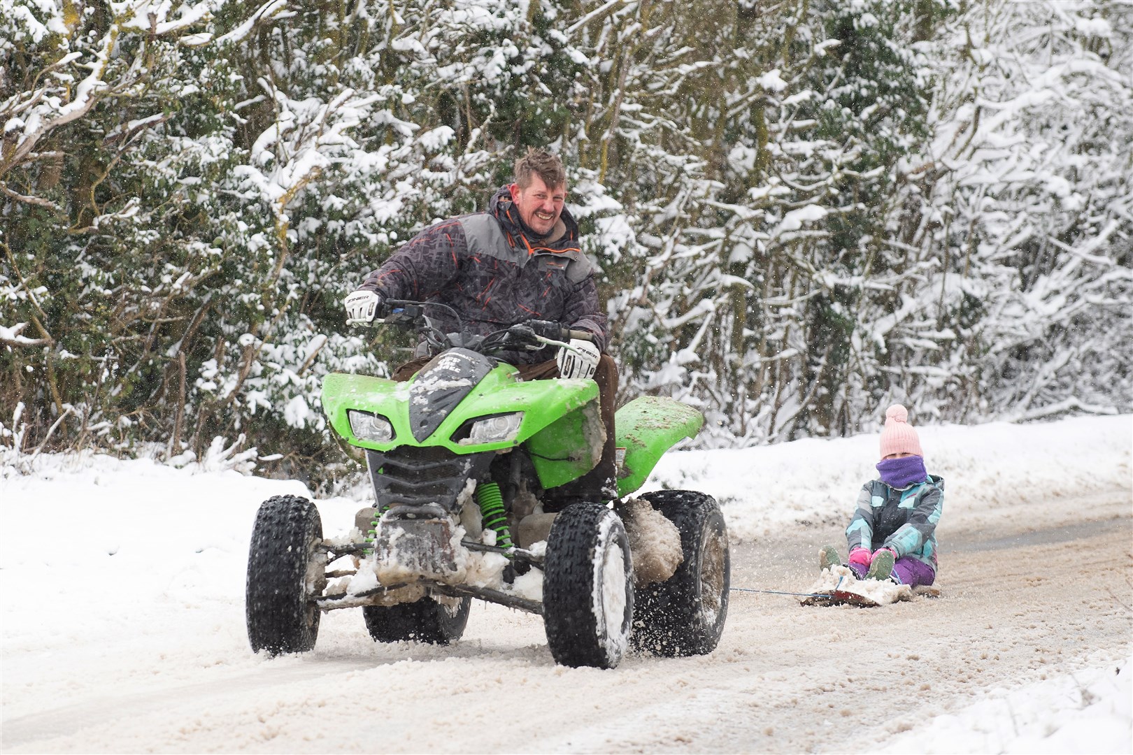 Richard Squirrell uses a quad bike to give his granddaughter Florence a ride in the snow in Wattisham in Suffolk (Joe Giddens/PA)