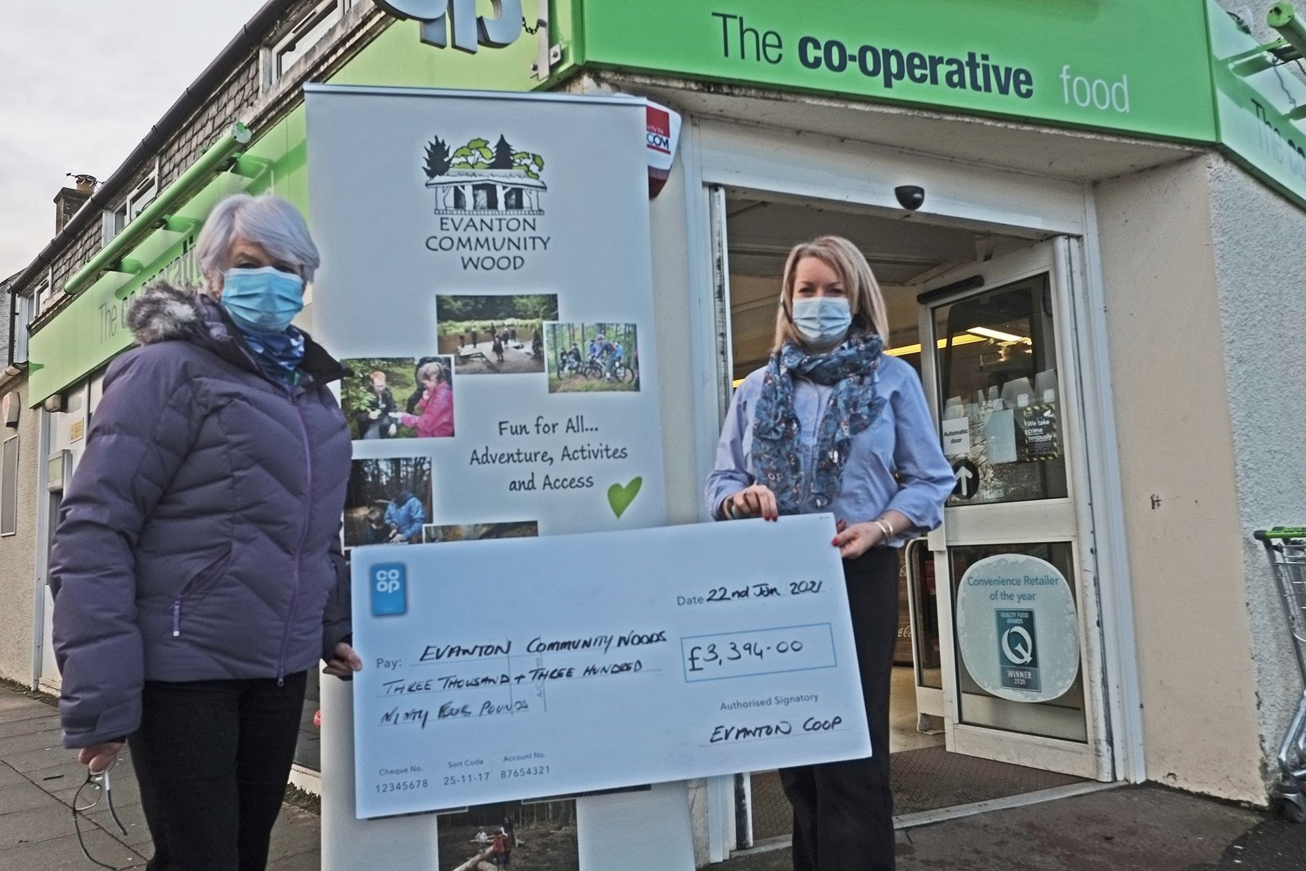 Linda Ross, Evanton Coop team leader (right) hands the cheque to Penny Gray, treasurer of the community wood.