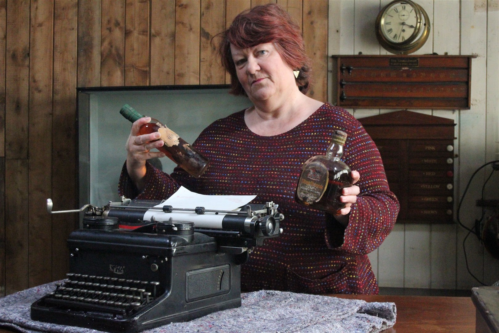 Fiona Mackenzie with Compton Mackenzie's typewriter and whisky bottles from S.S Politician. Picture: Canna House Archive, National Trust for Scotland.