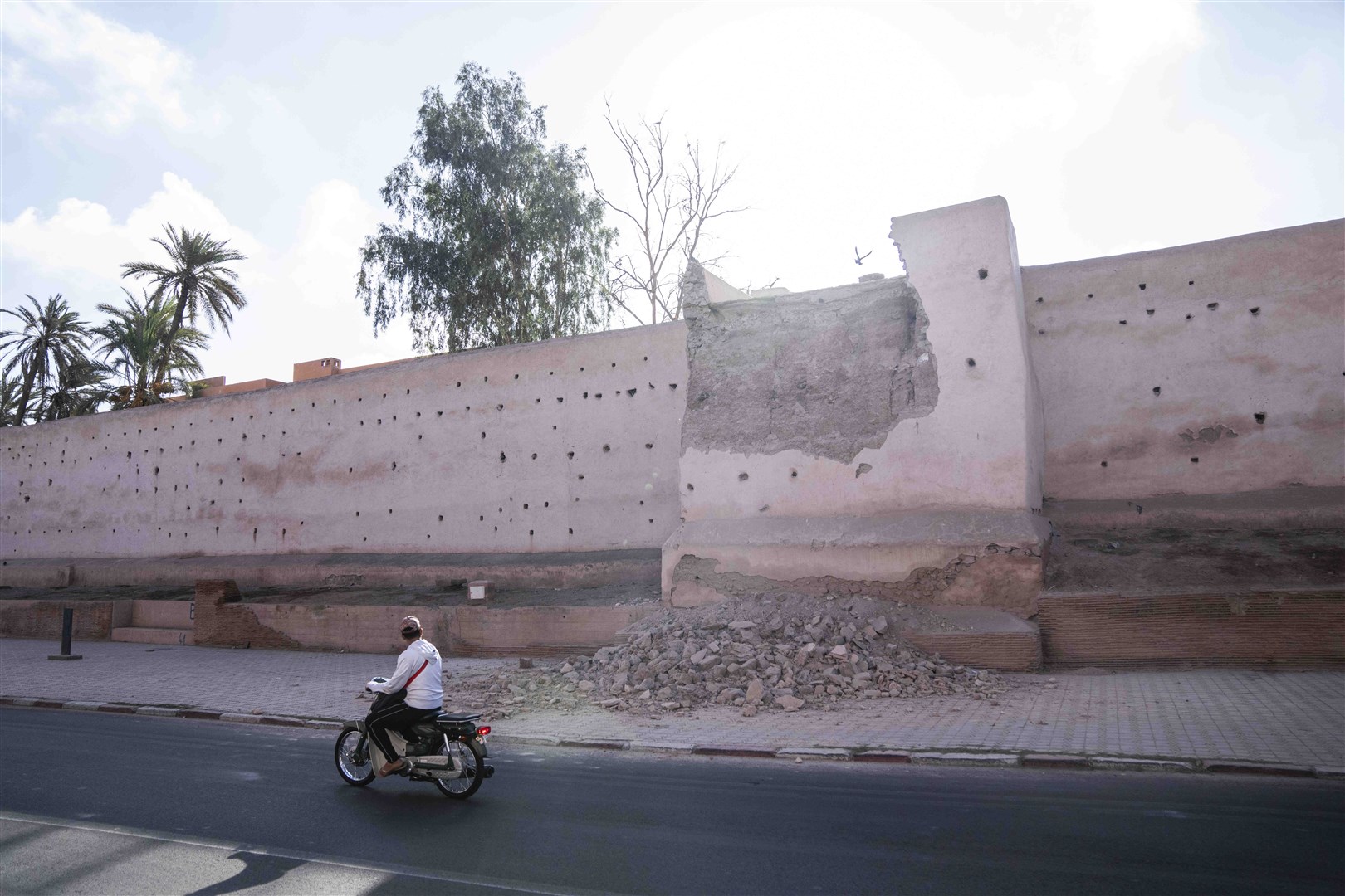 A man drives past a damaged wall of the historic Medina of Marrakesh (Mosa’ab Elshamy/AP/PA)