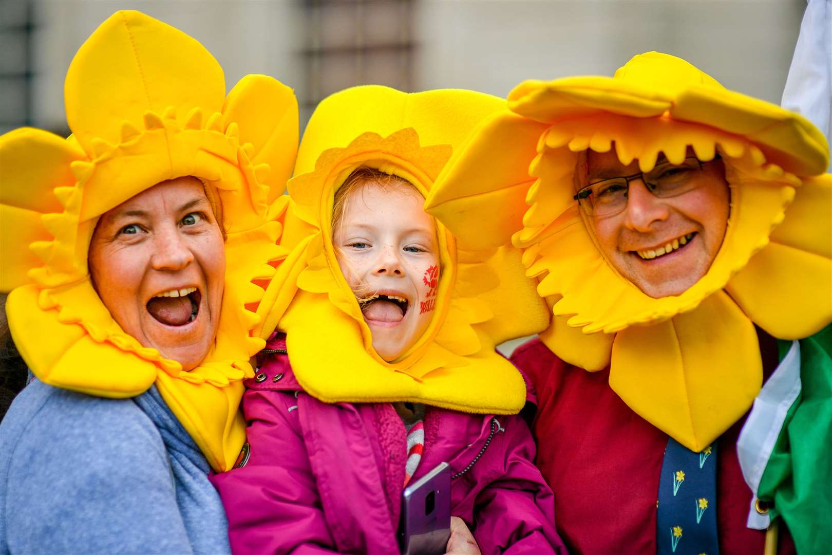 Kim Milhench, left, Grace Whitton and Mark Selby dress as daffodils during a St David’s Day parade in Cardiff (Ben Birchall/PA)