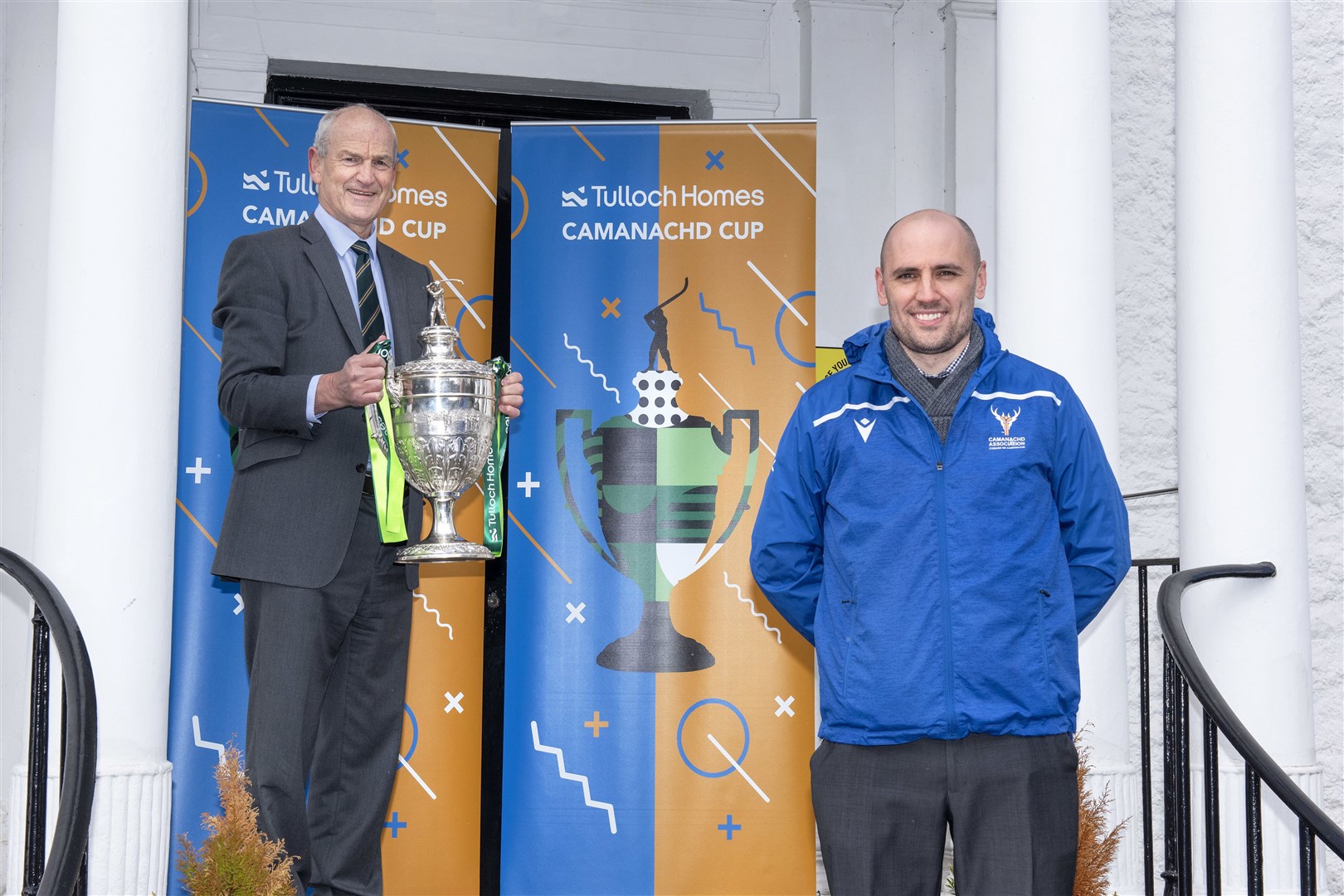 George Fraser (left), former Newtonmore player & Tulloch Homes CEO holds the Tulloch Homes Camanachd Cup alongside Camanachd Association CEO, Derek Keir.