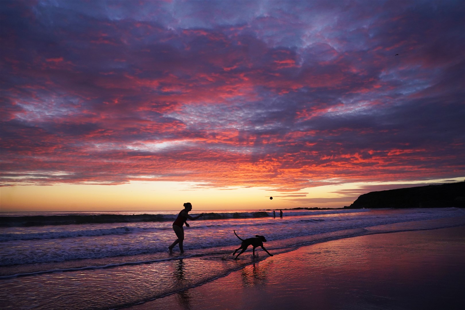 A beautiful sunrise along the Northumberland coast provided the perfect backdrop for some fun on the beach for this dog owner and her pet (Owen Humphreys/PA)
