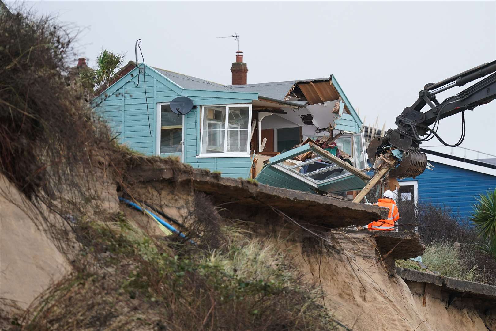 Demolition workers tear down the first of five clifftop homes in the village of Hemsby which has been hit by coastal erosion (Joe Giddens/PA)