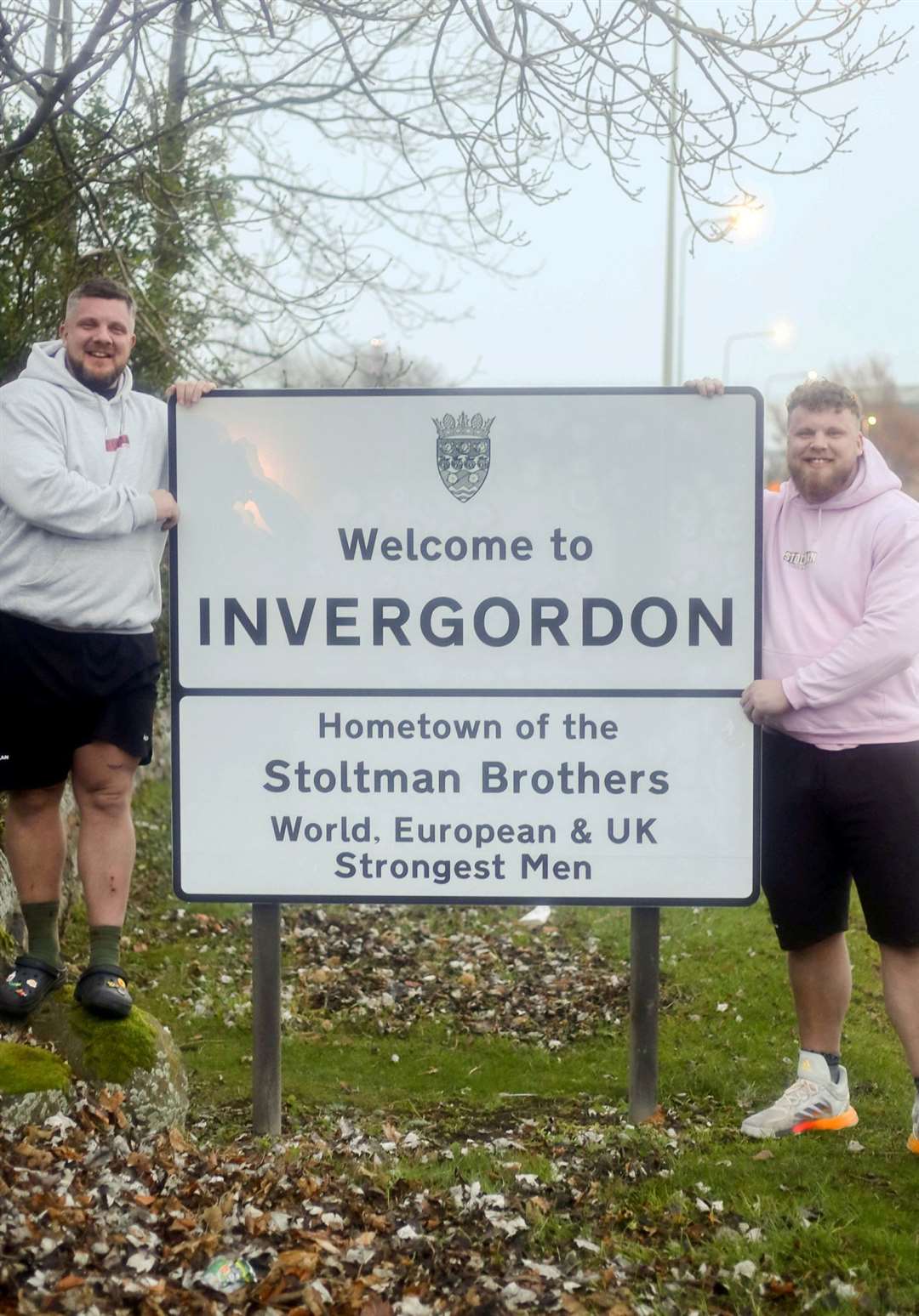 The Stoltman brothers Luke and Tom in front of a Welcome to Invergordon sign made in their honor.  Photo: James Mackenzie