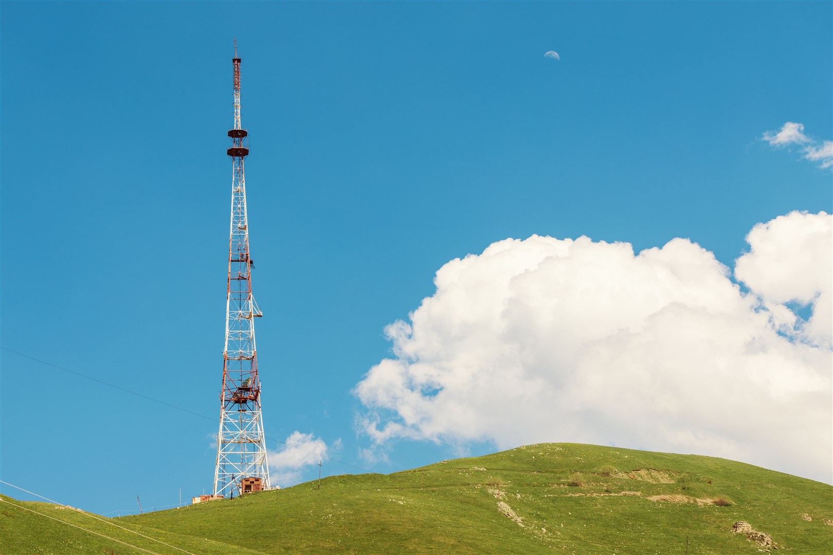 A cellular tower for communication on a hill in a rural area.