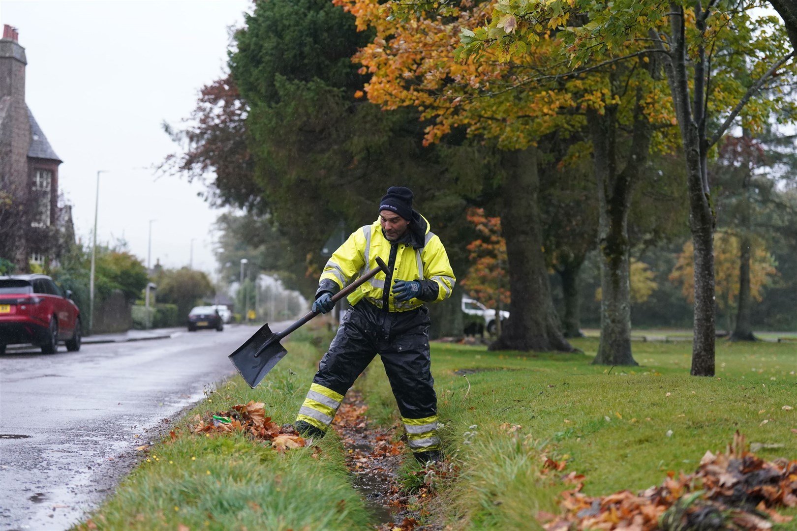 A workman clears a drainage ditch in the village of Edzell, Scotland (Andrew Milligan/PA)