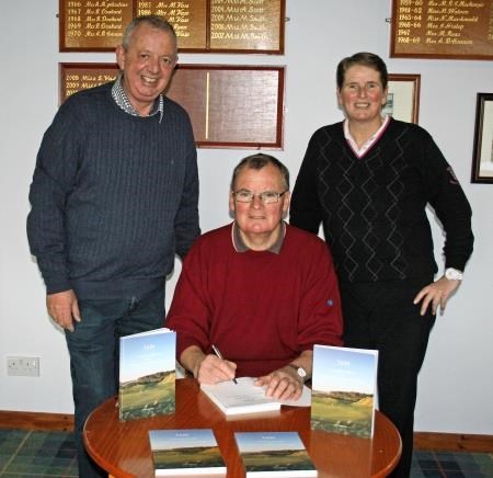 Tony Watson signing copies of his book in the Tain Clubhouse watched over by the Club Captain, Ewan Forrest (left) and club secretary Maggie Vass