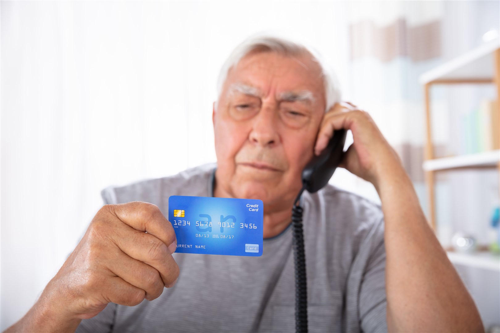 Close-up Of A Senior Man With Credit Card Using Landline Phone