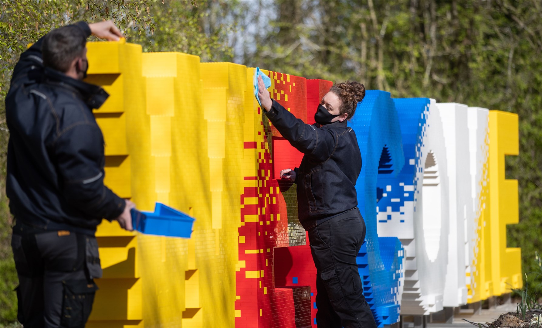 Legoland model makers Nicola Parker (right) and Elliott Ayton-Smith clean and add bricks to a welcome sign at the Legoland Windsor Resort, as they prepare to welcome back visitors (Andrew Matthews/PA)