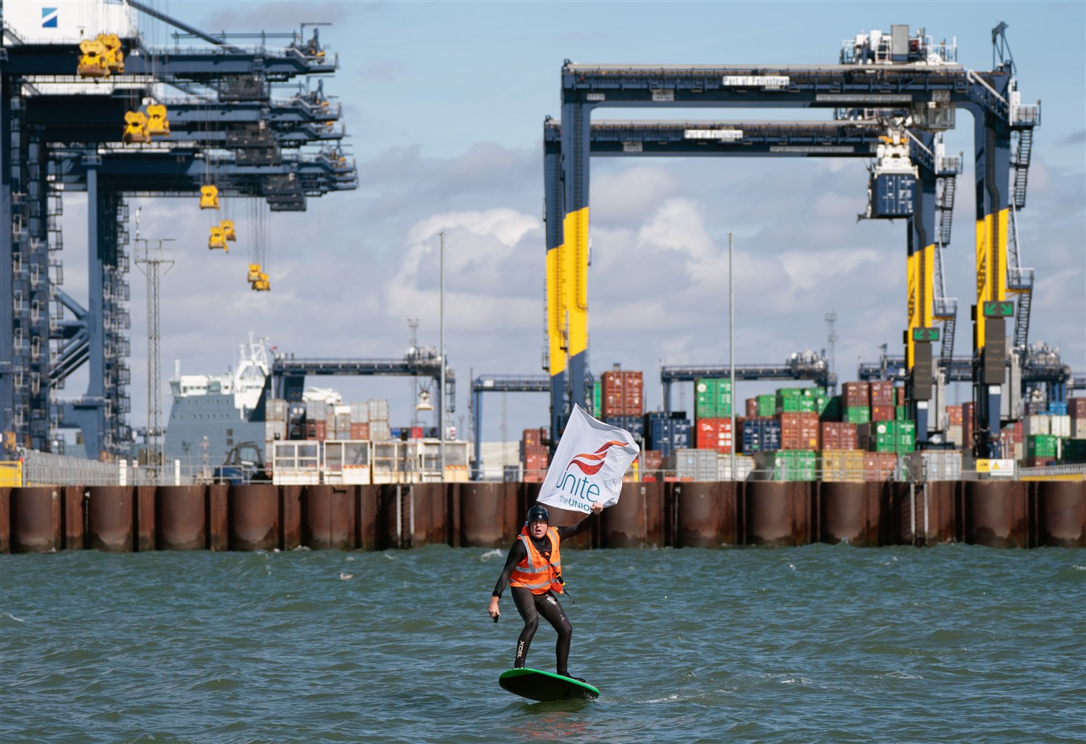 A man carrying a Unite the Union flag surfs around the Port of Felixstowe in Suffolk where members of the Unite union are on strike at Britain’s biggest and busiest container port (Joe Giddens/ PA)
