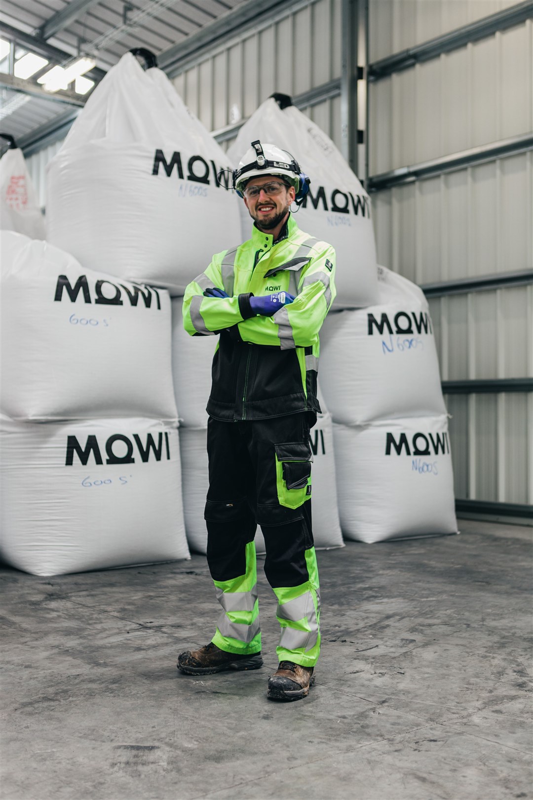 Mowi employee Chris MacRae inside the feed mill in front of bags of fish feed produced there.