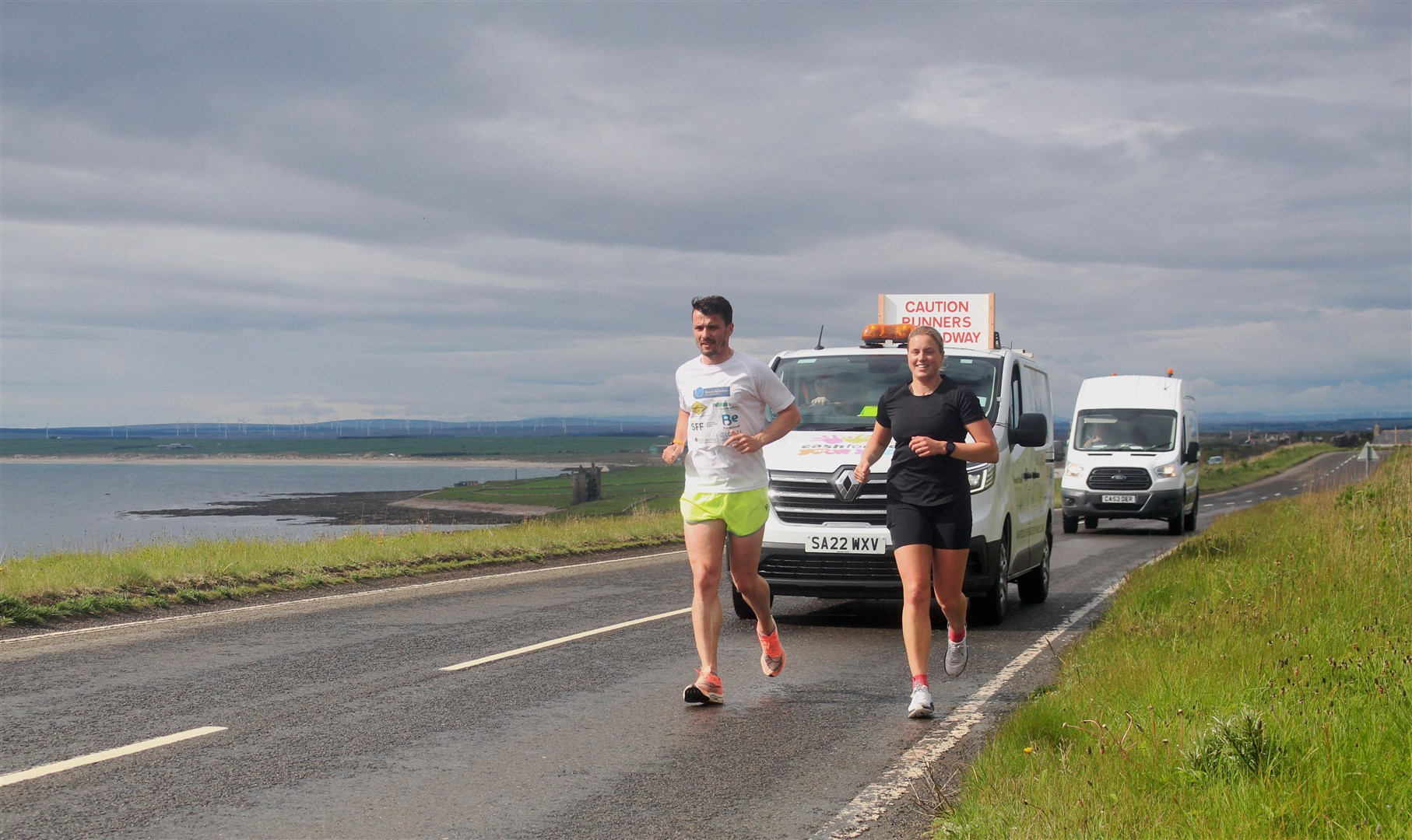 Steven Mackay and fellow runner Seana Forbes making their way past Sinclair's Bay on Sunday, with Keiss Castle in the distance. Picture: Alan Hendry