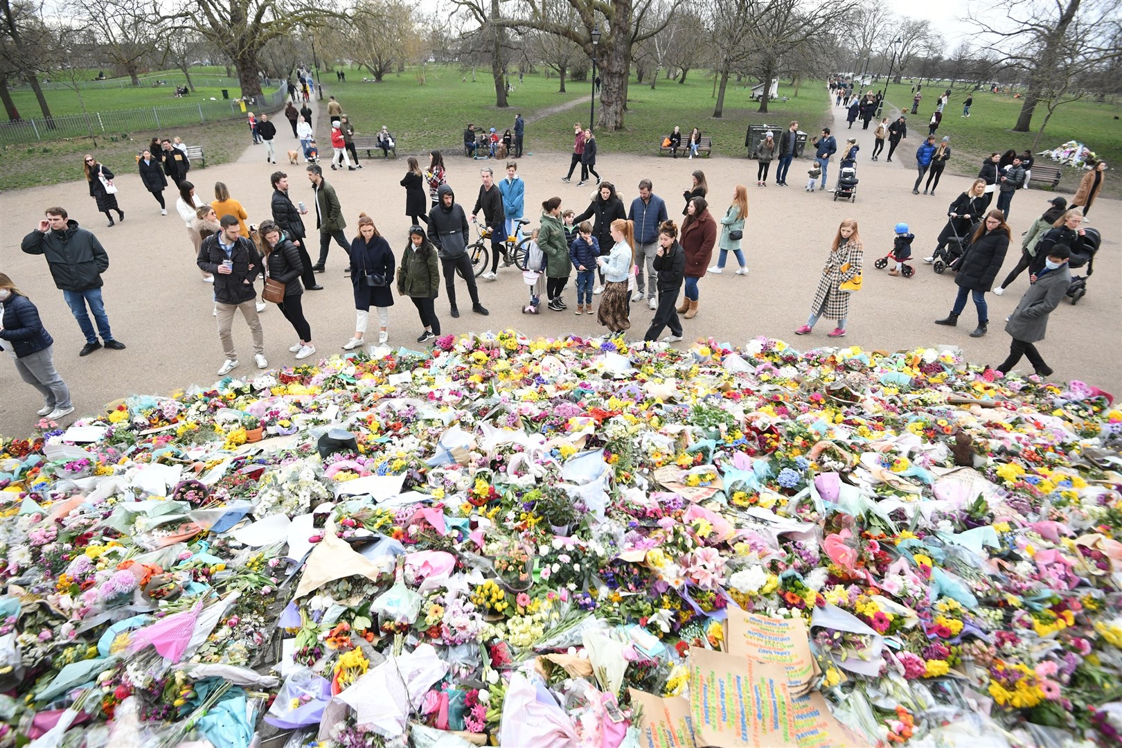 People viewing floral tributes left at the bandstand in Clapham Common, London, for Sarah Everard (Victoria Jones/PA)