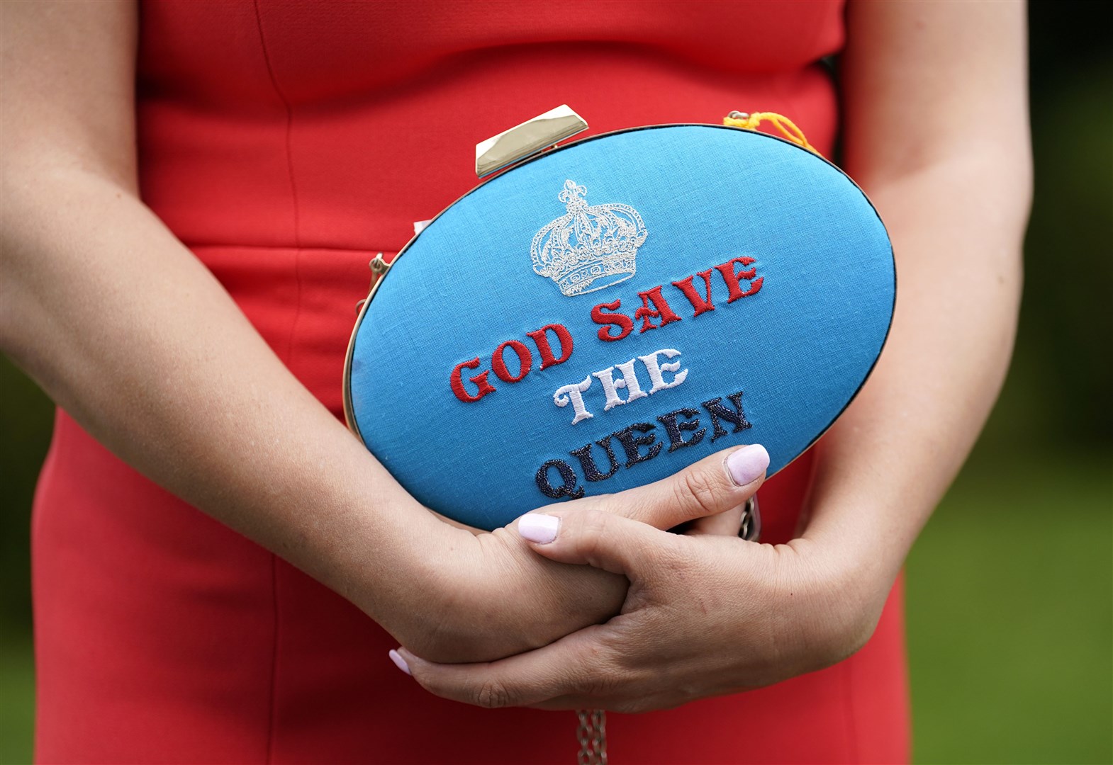 Racegoer Anna Gilder holds a God Save The Queen clutch bag on Ladies Day during the Derby Festival at Epsom Racecourse (Andrew Matthews/PA)