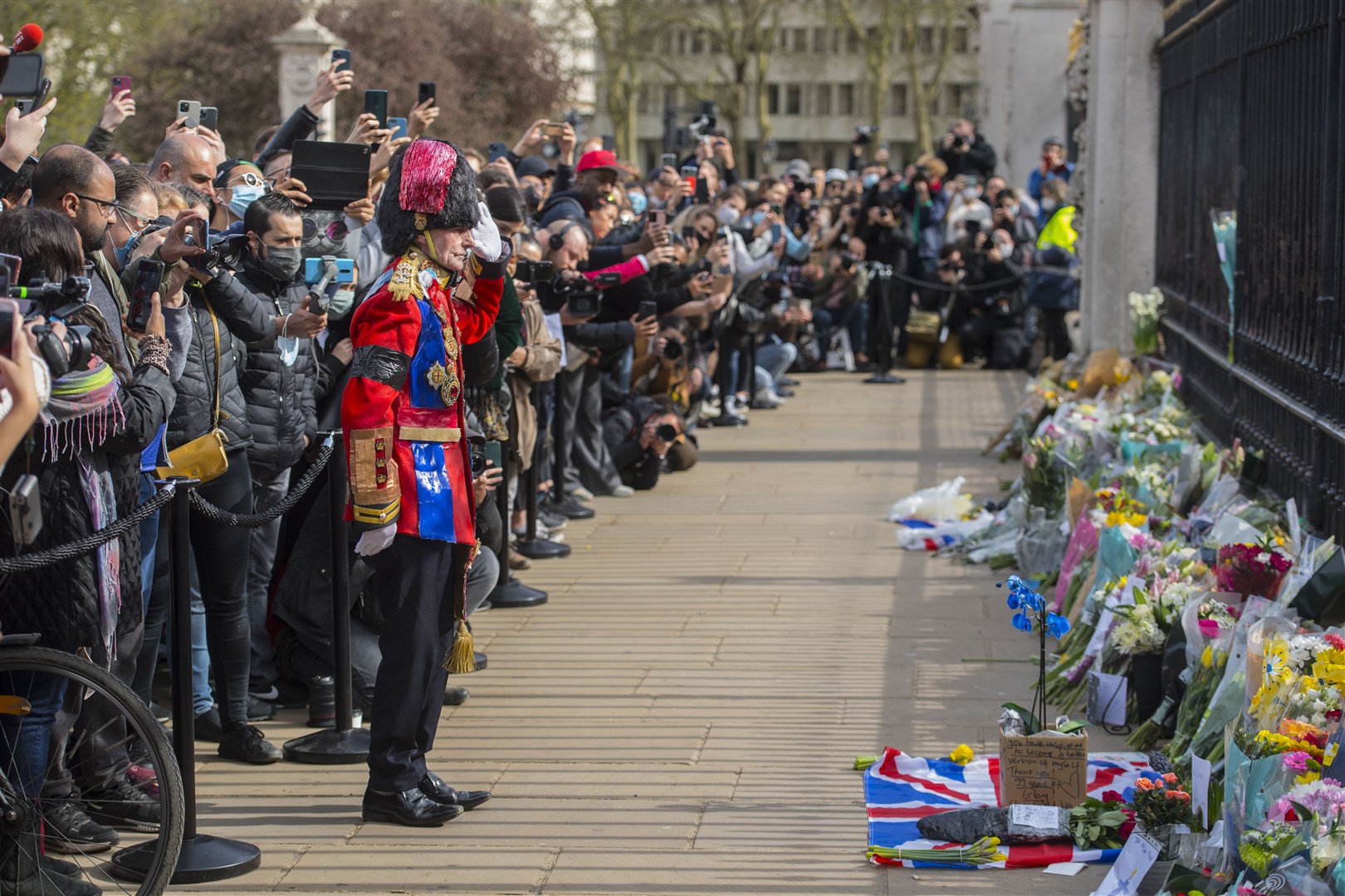 A man lays a floral tribute outside Buckingham Palace (Ian West/PA)