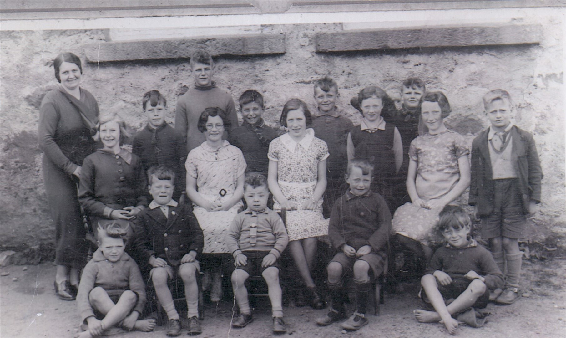 A photograph of the teacher and pupils at Laide School in 1936.Back row, l-r: Miss Munro (teacher), Angus MacKenzie, Willie MacAulay, Alistair MacKenzie, Hughie MacKenzie, Allan MacAulay, Bertie MacLennan. Middle row, l-r: Ina MacKenzie, Kathy Campbell, Katie MacKenzie, Peggy MacLean, Nina MacKenzie. Front row, l-r: Charlie MacKenzie, Don and William MacKenzie (brothers of Alistair), Donald MacLean, Kenny MacKenzie. Miss Munro was one of the individuals from the area who features in the recordings.