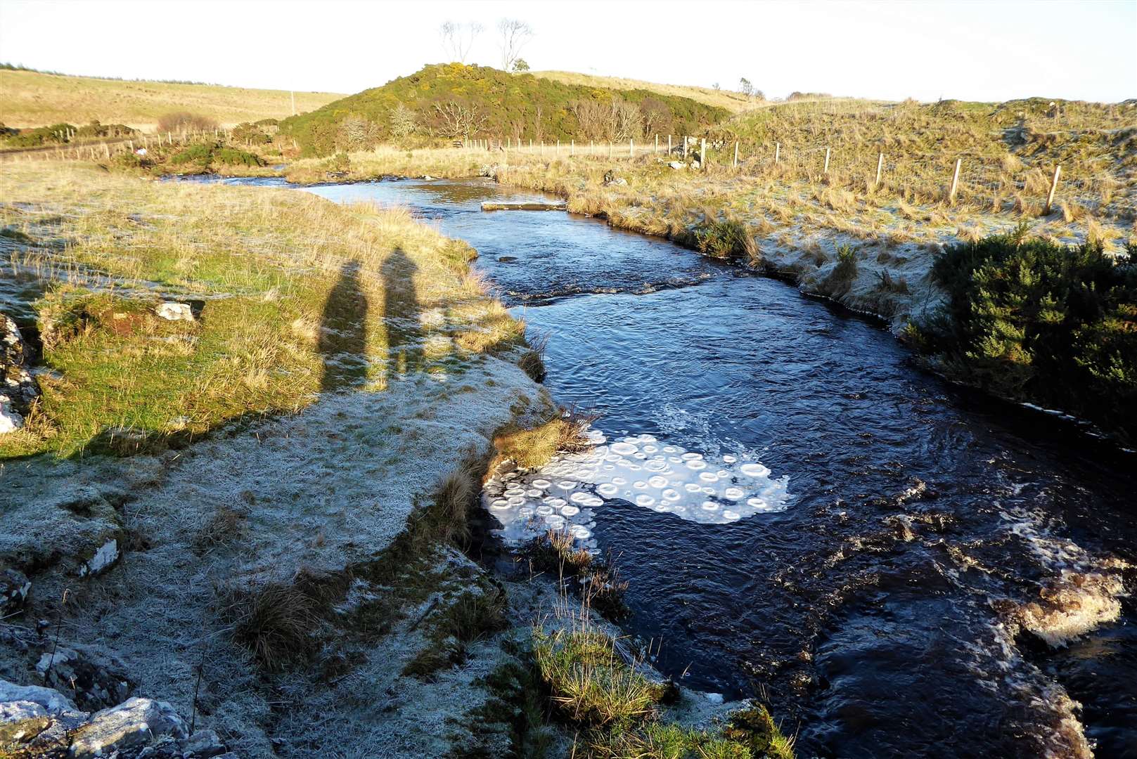 Frozen pancakes at Scouthal Burn.  Cuckoo Hill is in the background and the remains of an old monastery and graveyard known as the Clow Chapel are on the right side.