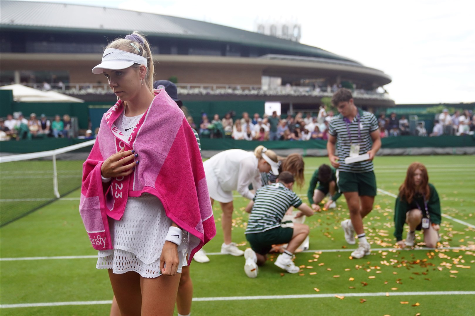Katie Boulter walks away as ground staff clear confetti from court 18 at Wimbledon (Adam Davy/PA)