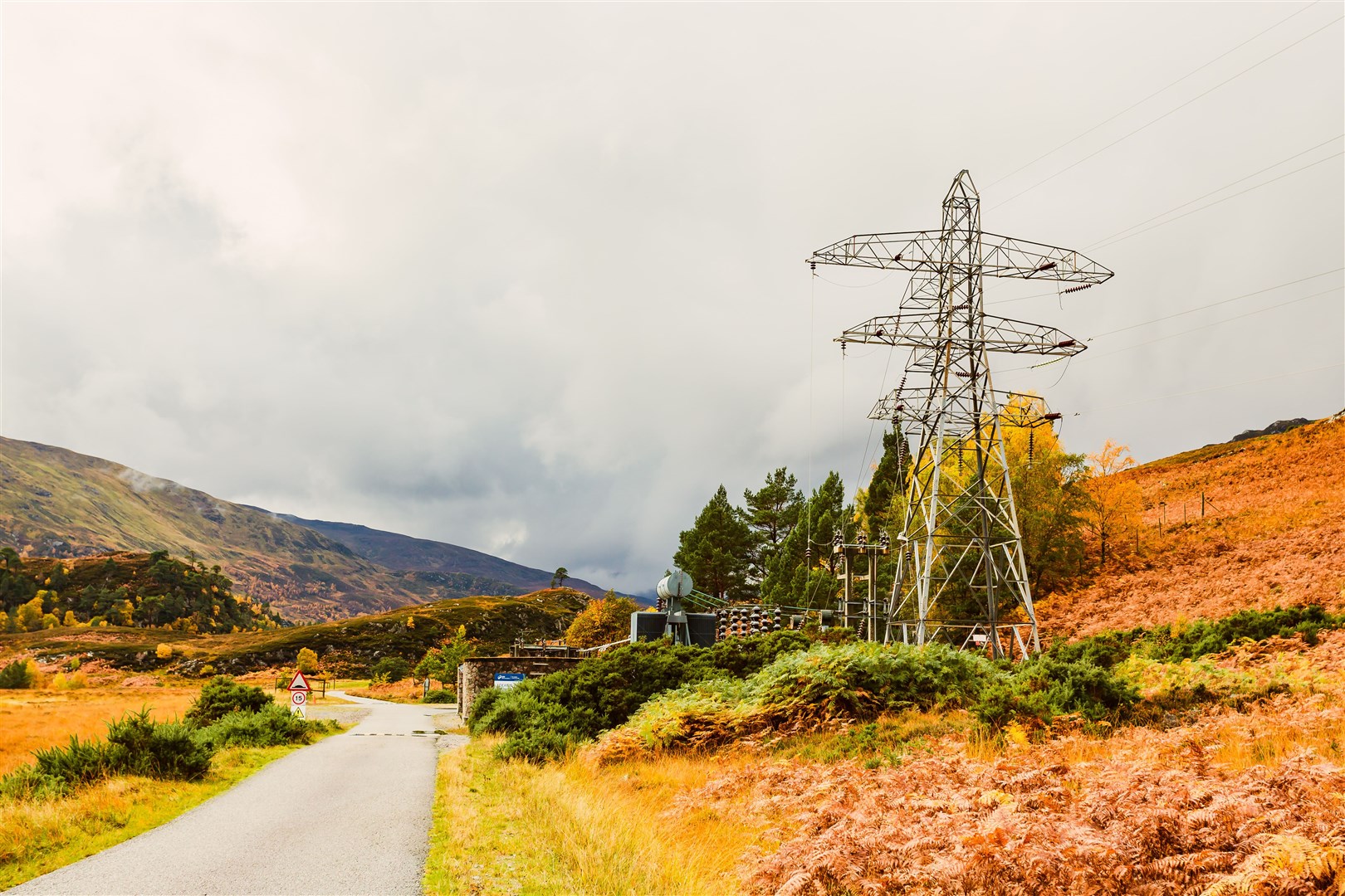 Deanie Power Station in the remote Glen Strathfarrar in the Scottish Highlands with pylon and power lines. Autumn with golden ferns. Copy space. Horizontal.