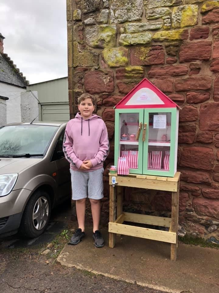 Alistair Fox (13) in front of his baking honesty box on Church Street in Cromarty.