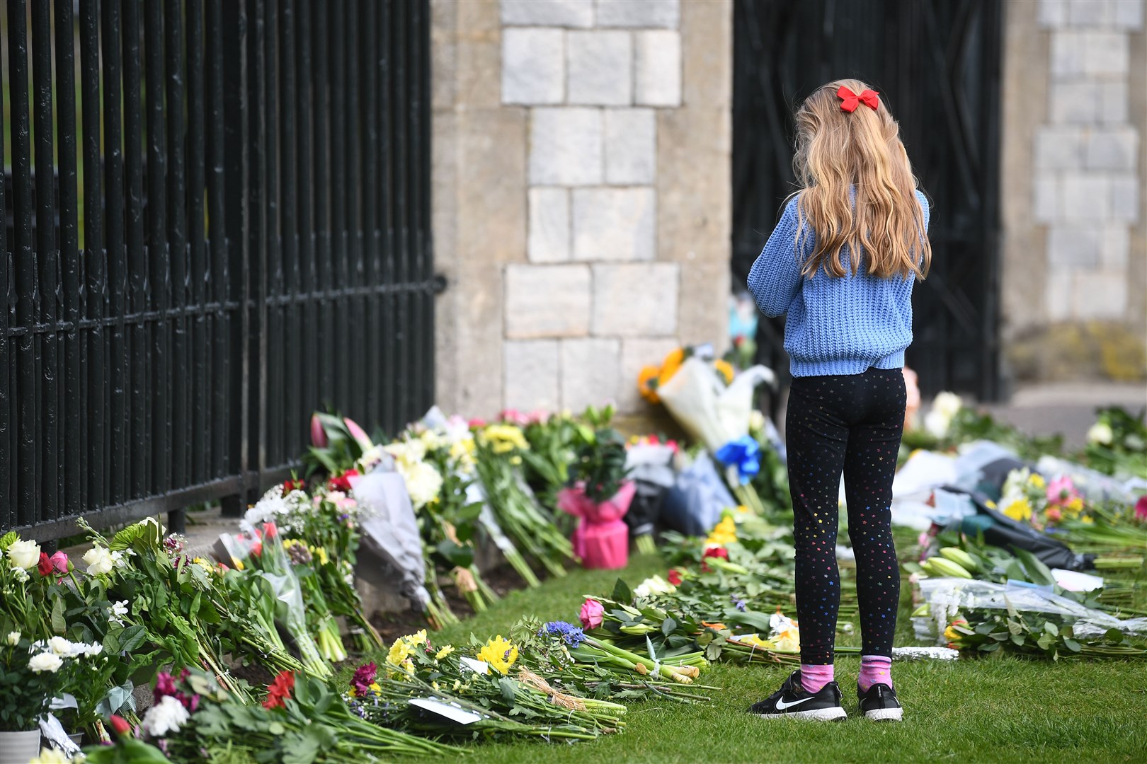 A young girl looks at flowers at Cambridge Gate at Windsor Castle (Victoria Jones/PA)