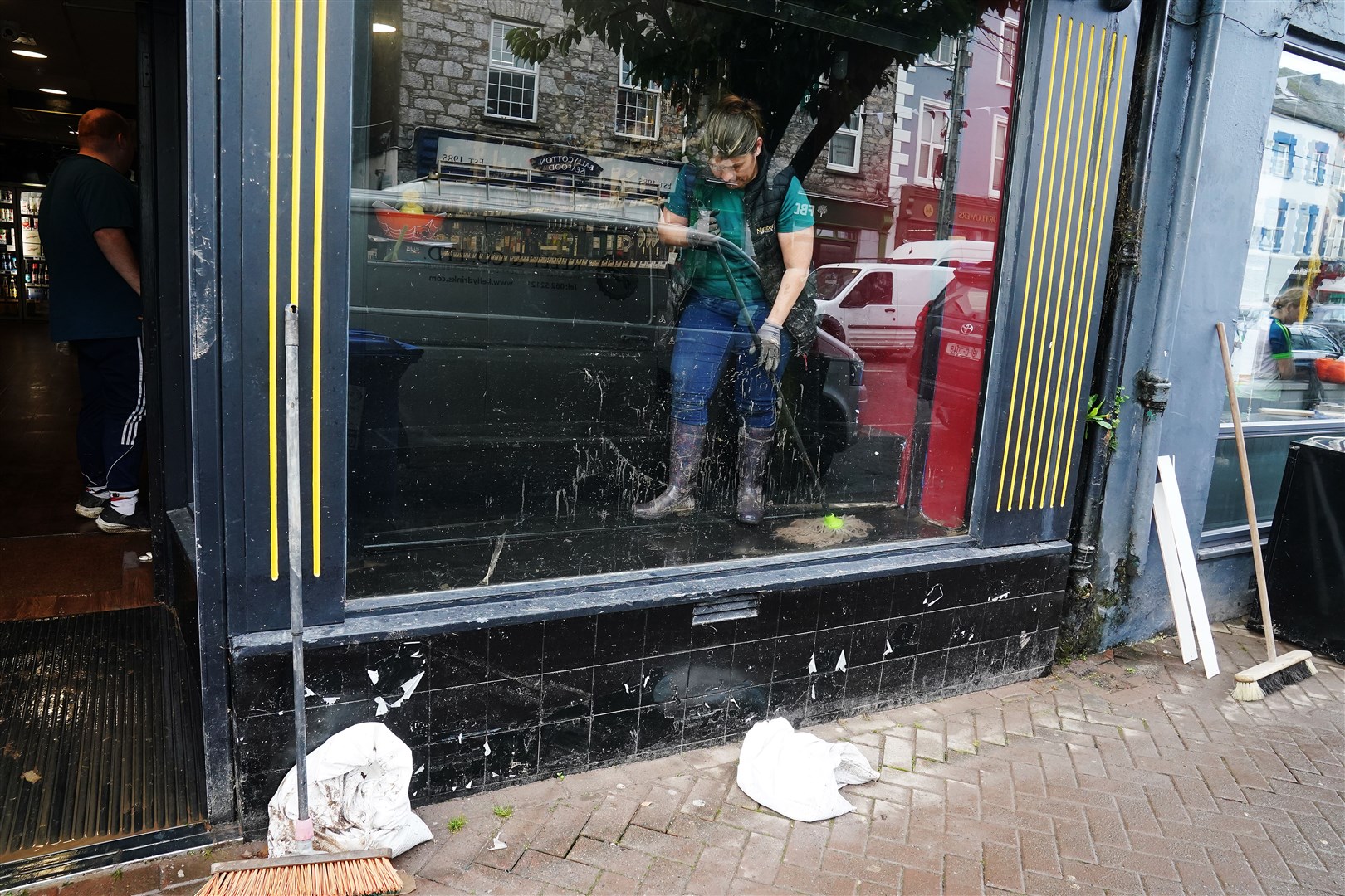 A shop owner mops the window of a shop front on Main Street in Midleton (Brian Lawless/PA)