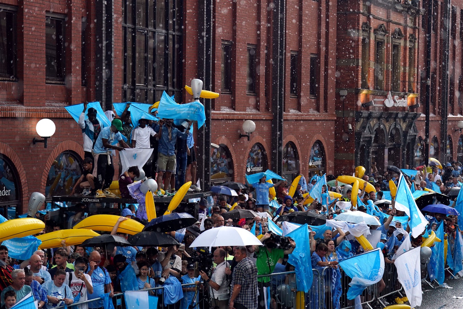 Manchester City fans take shelter from the rain (Tim Goode/PA)