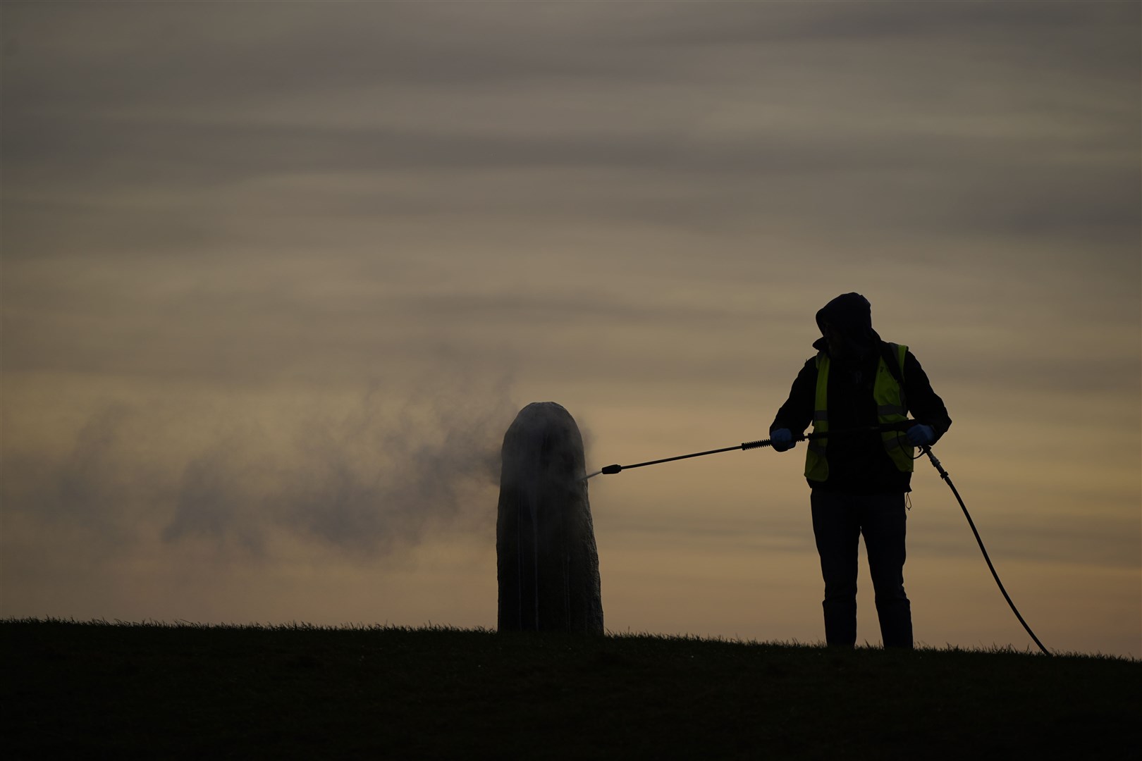 A worker from the office of public works begin the clean up of graffiti on the Lia Fail standing stone, which is also known as the Stone of Destiny, on the Hill of Tara near Skryne in County Meath (Niall Carson/PA)