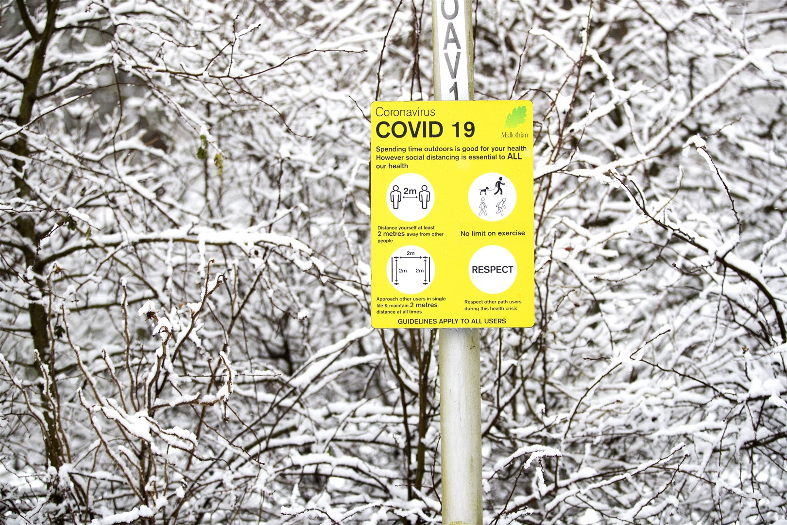 A coronavirus information sign surrounded by snow in Auchendinny, Midlothian (Jane Barlow/PA)