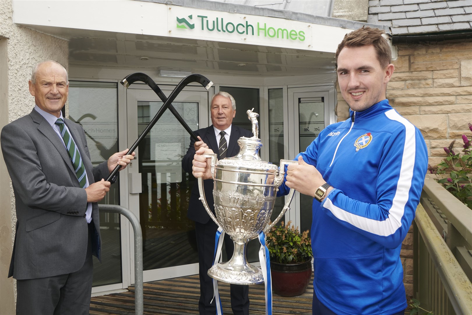 Michael Russell, captain of Camanachd Cup holders Newtonmore, with trophy, flanked by Association president Keith Loades and George Fraser, chief executive of sponsors Tulloch Homes.