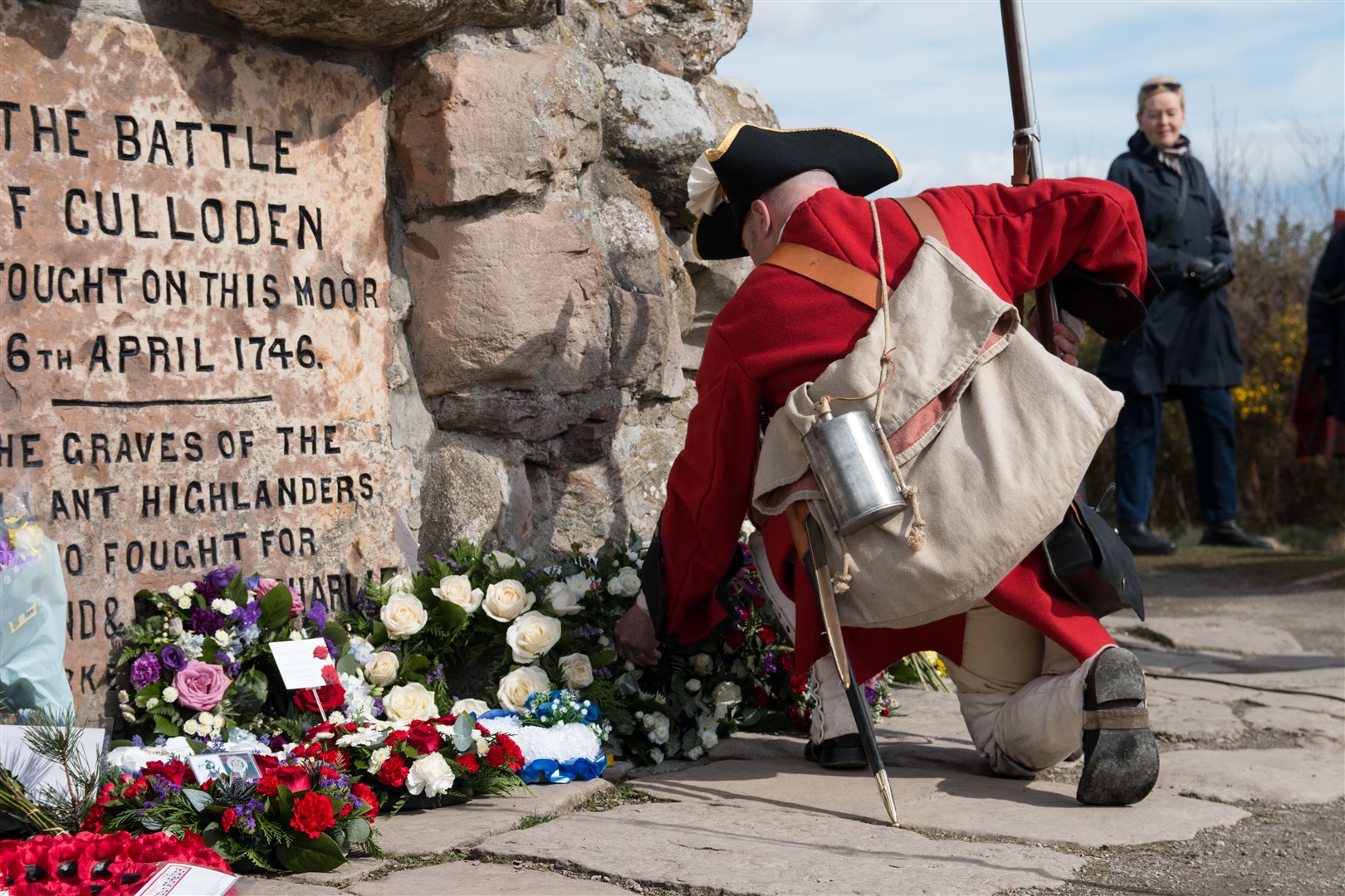 A man wearing the outfit of the Irish Piquets places at wreath at the battlefield cairn.