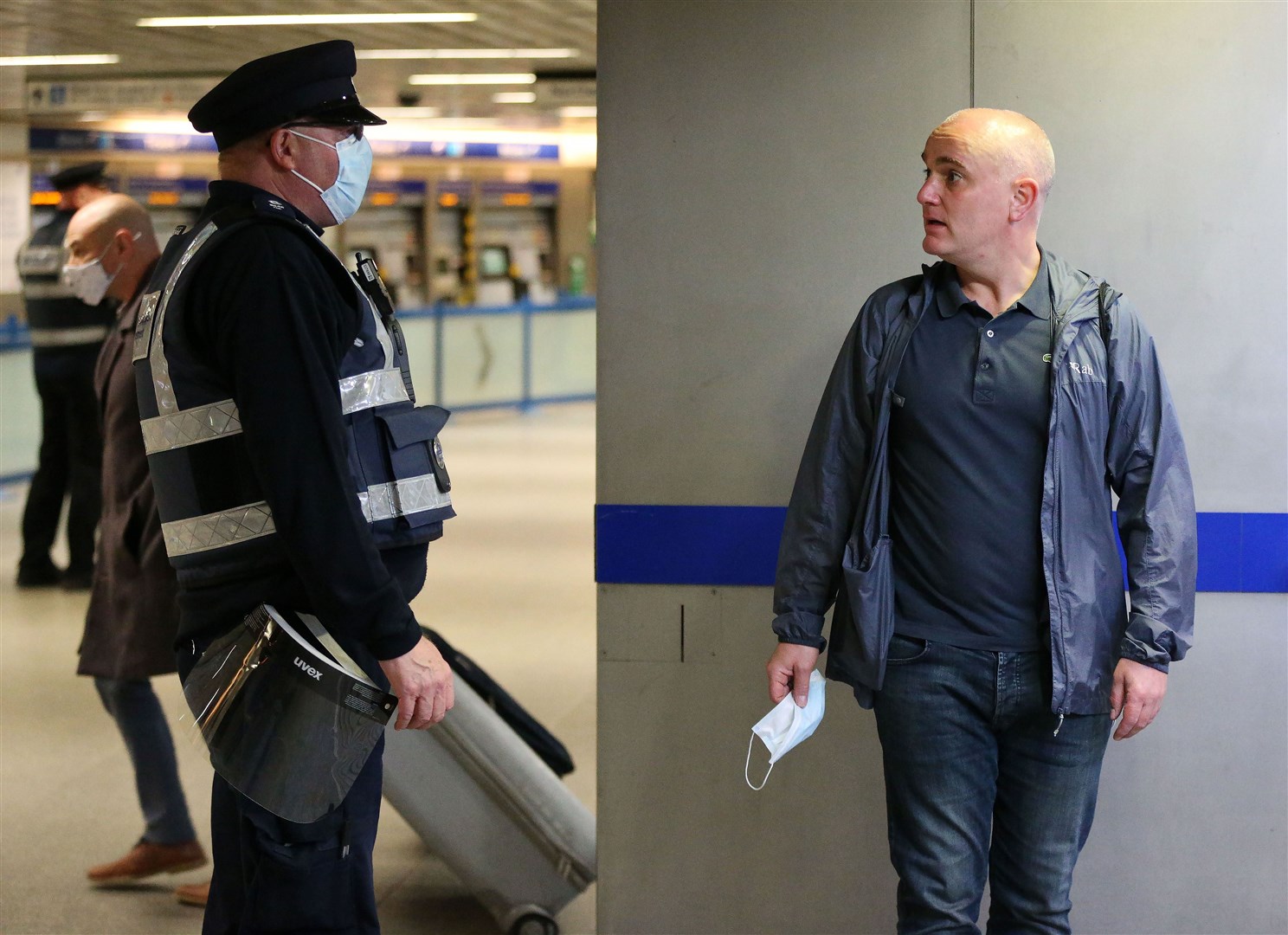 A man holds his face mask while being spoken to by a TfL staff member (Jonathan Brady/PA)