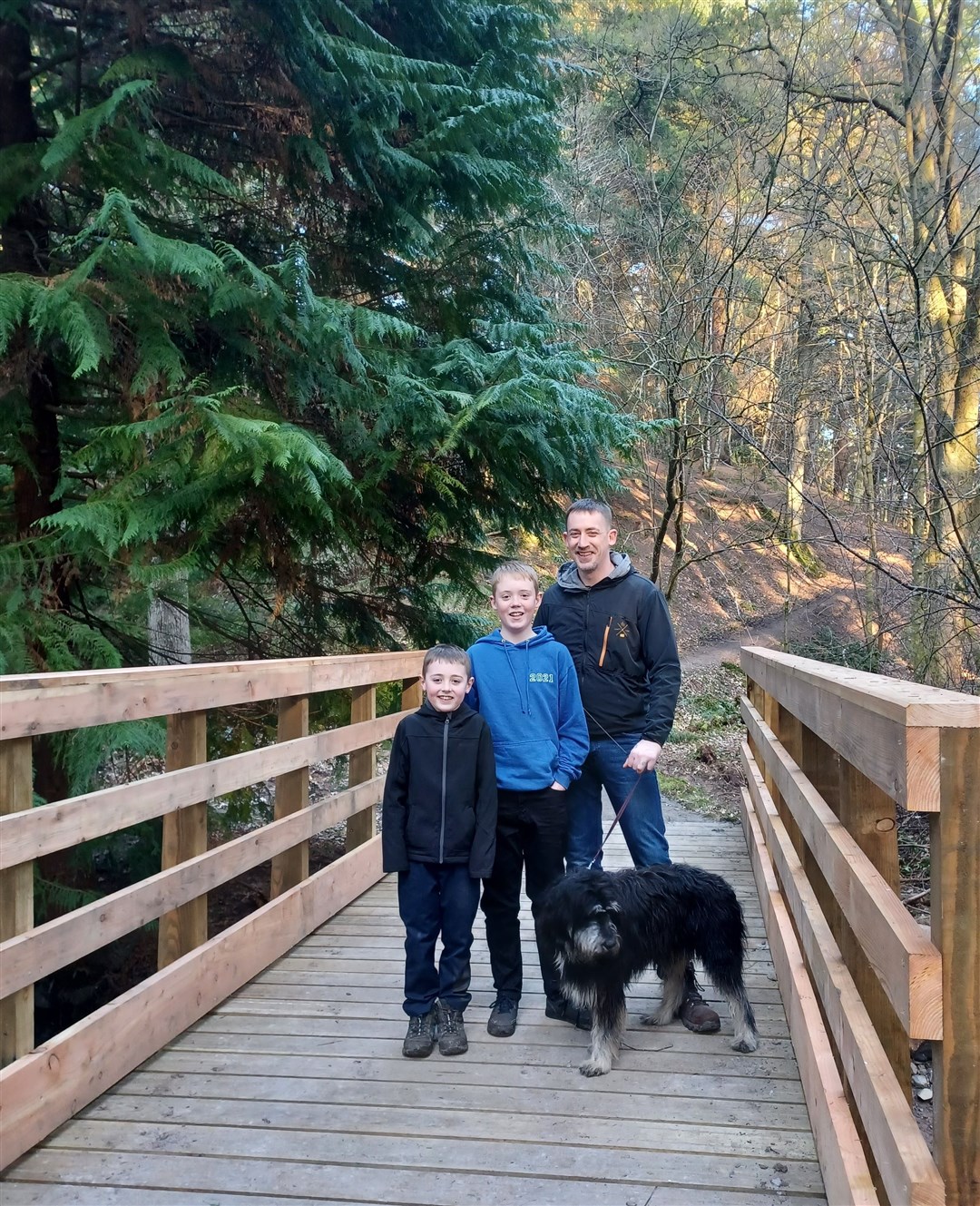 James Thompson and sons Charlie and Cameron enjoy walking their dog in the woods.