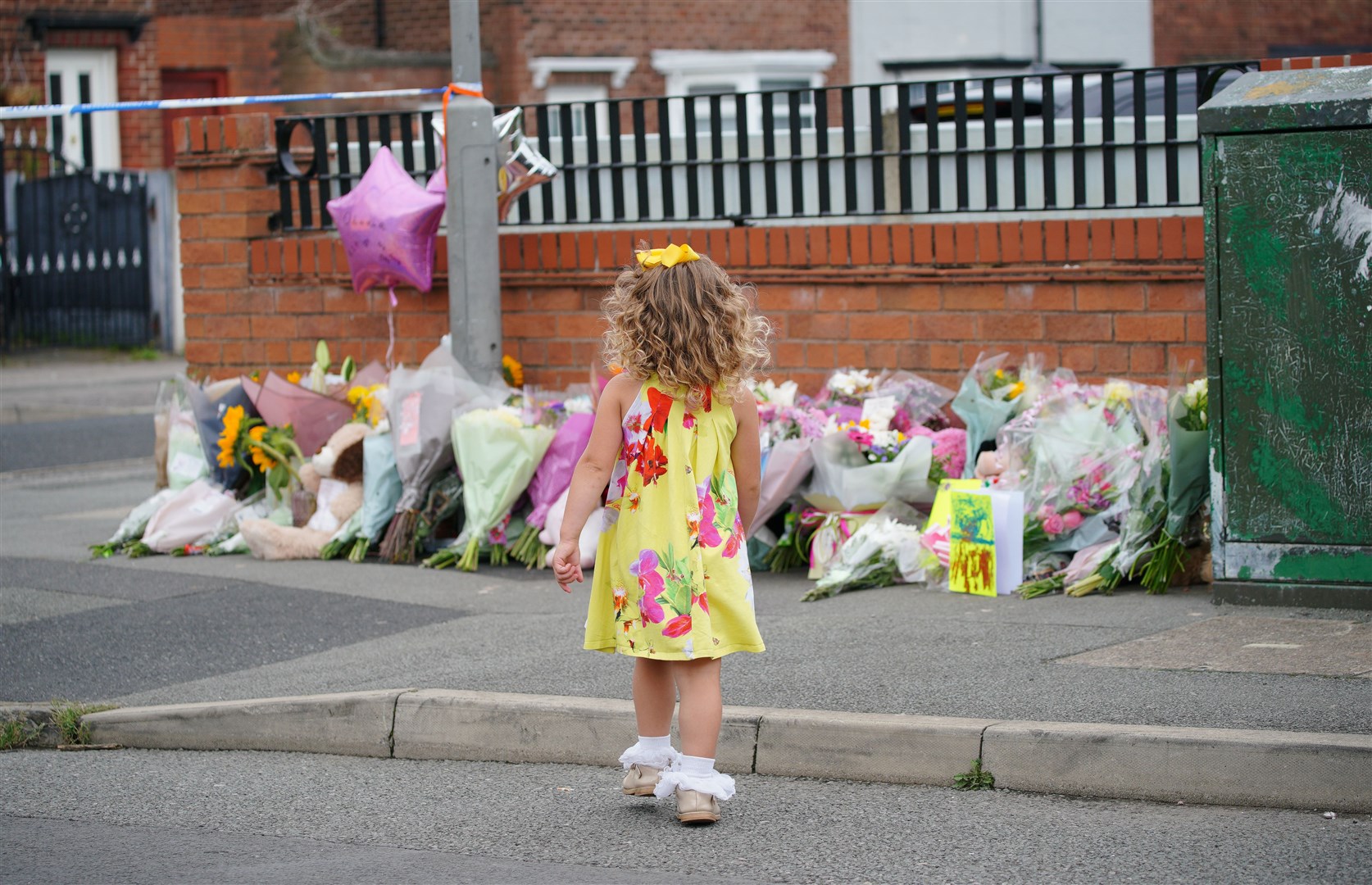 A young girl lays a tribute in Kingsheath Avenue, Liverpool, where nine-year-old Olivia Pratt-Korbel was fatally shot (Peter Byrne/PA)