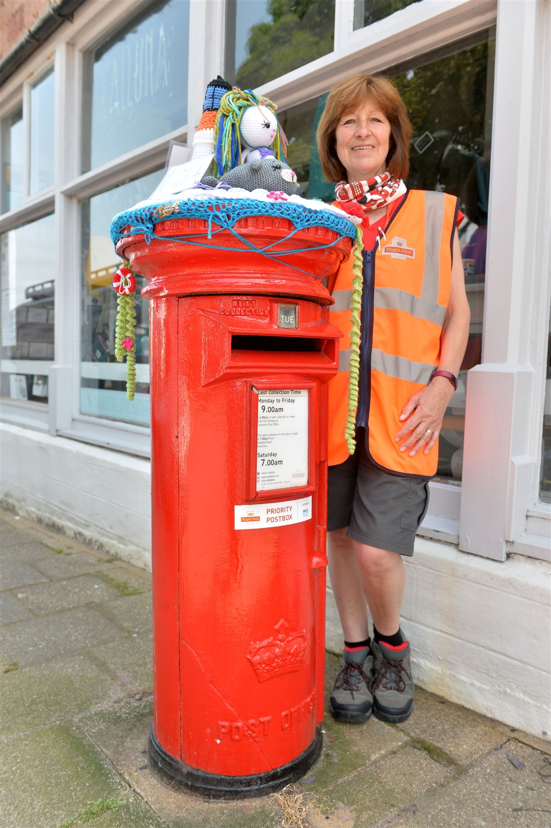 Local postie Wilma Stewart in Cromarty and the postbox that was yarn bombed. Picture: Callum Mackay