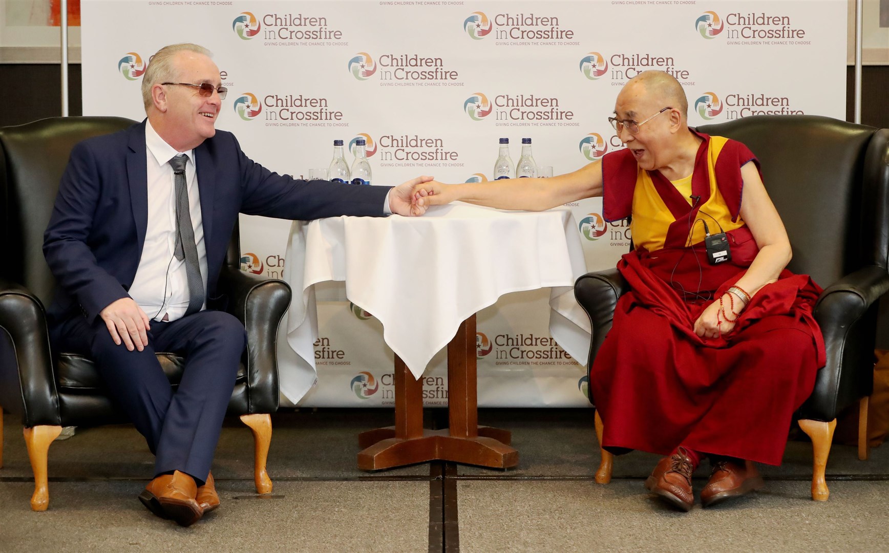 The Dalai Lama (right) holds hands with Children In Crossfire chief executive Richard Moore while speaking at the City Hotel in Londonderry (Niall Carson/PA)