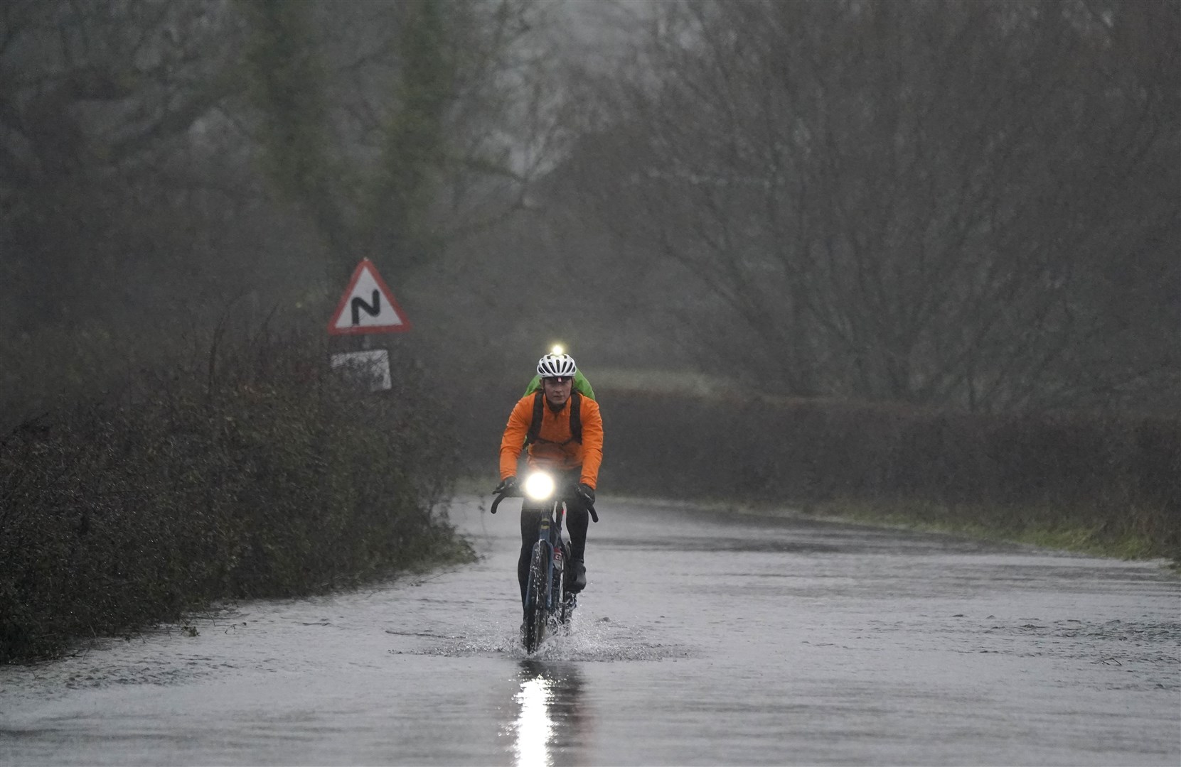 A cyclist makes their way through flood water on Kent Lane, near to Ibsley in Hampshire on Tuesday (Andrew Matthews/PA)