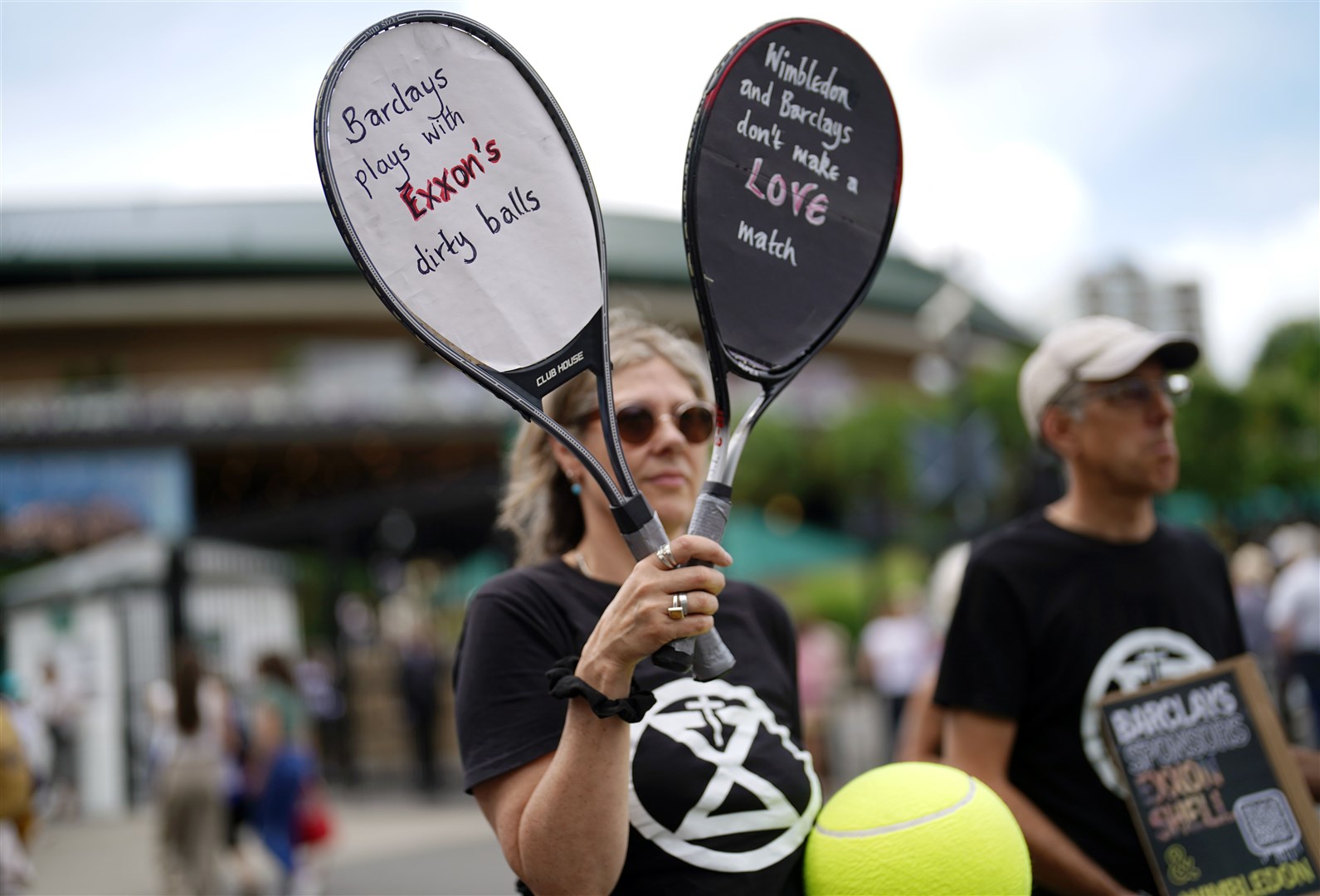 Rachie Ross holding up signs outside of the Wimbledon gates (Victoria Jones/PA)