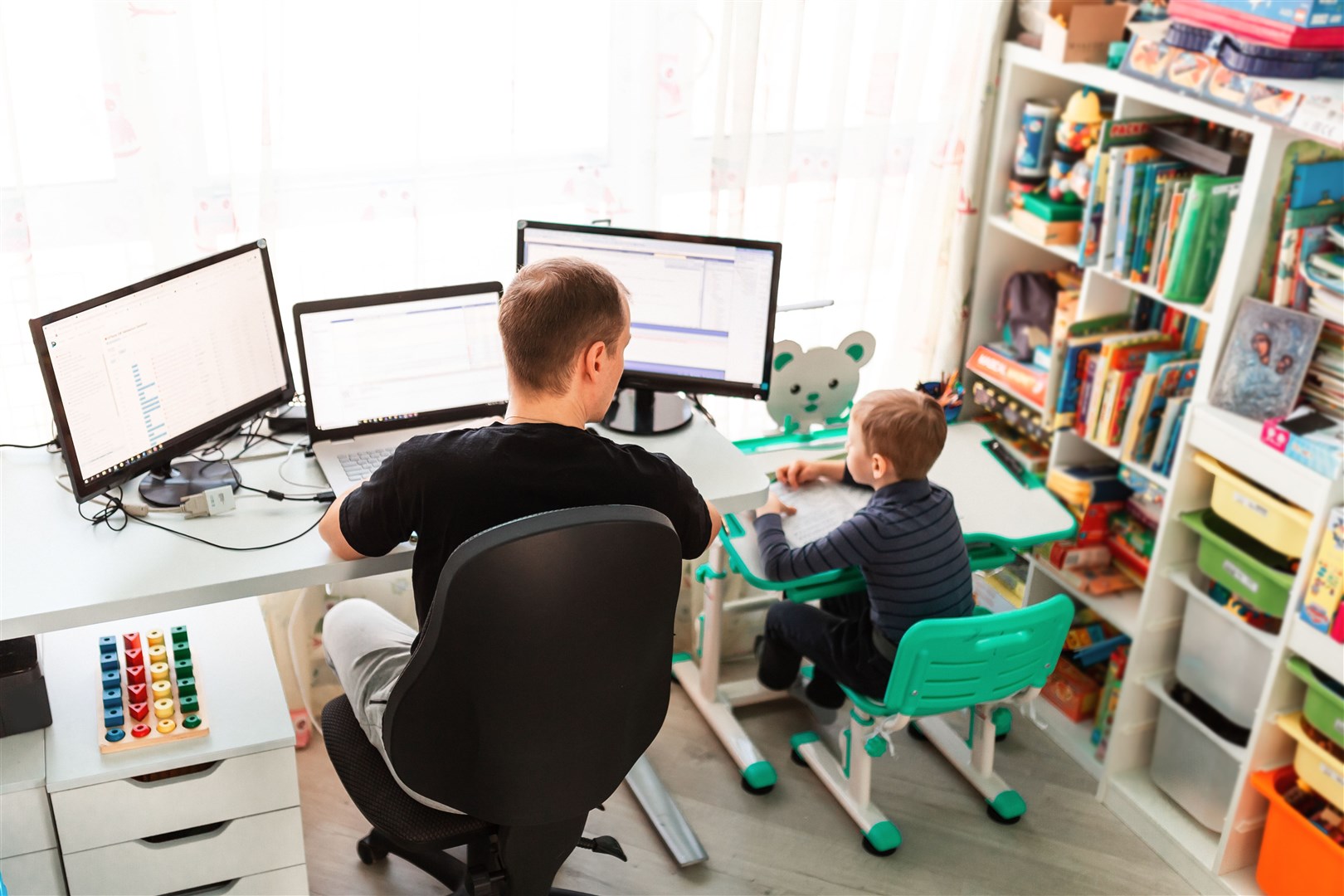 Father with kid trying to work from home during quarantine. Stay at home, work from home concept during coronavirus pandemic