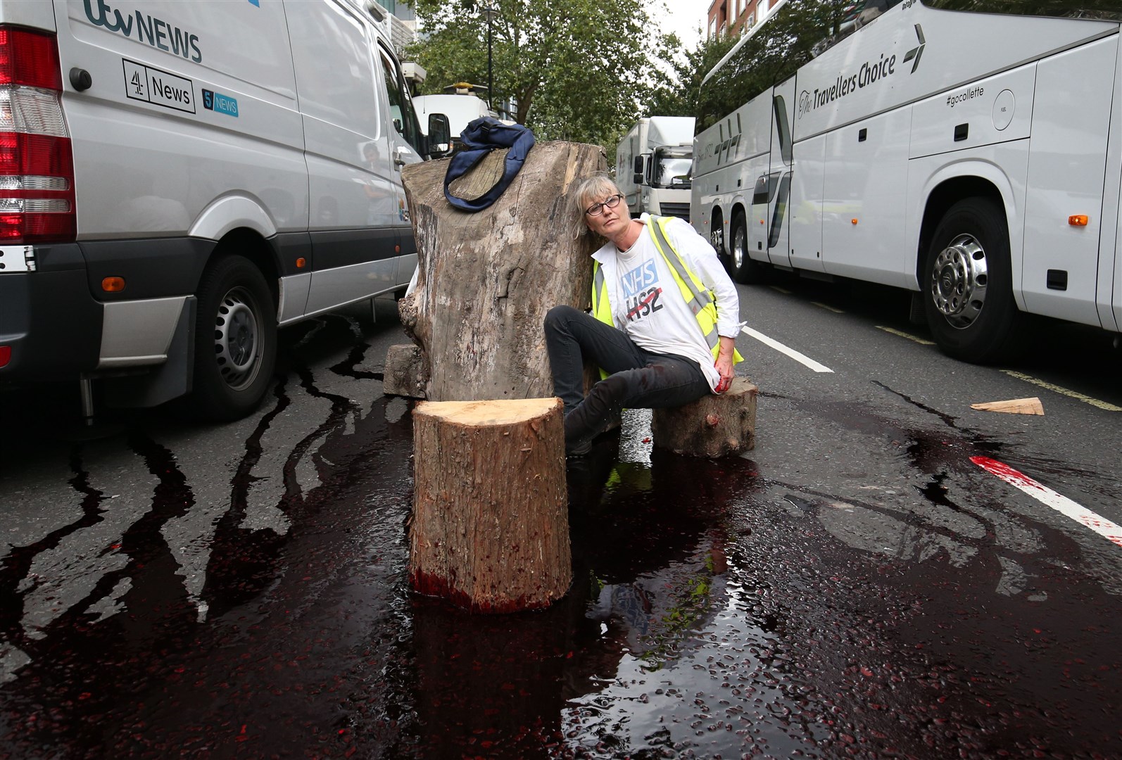 Extinction Rebellion protesters have poured fake blood over the road before being glued to each other through a hallowed-out tree trunk outside the Home Office in Westminster (Jonathan Brady/PA)
