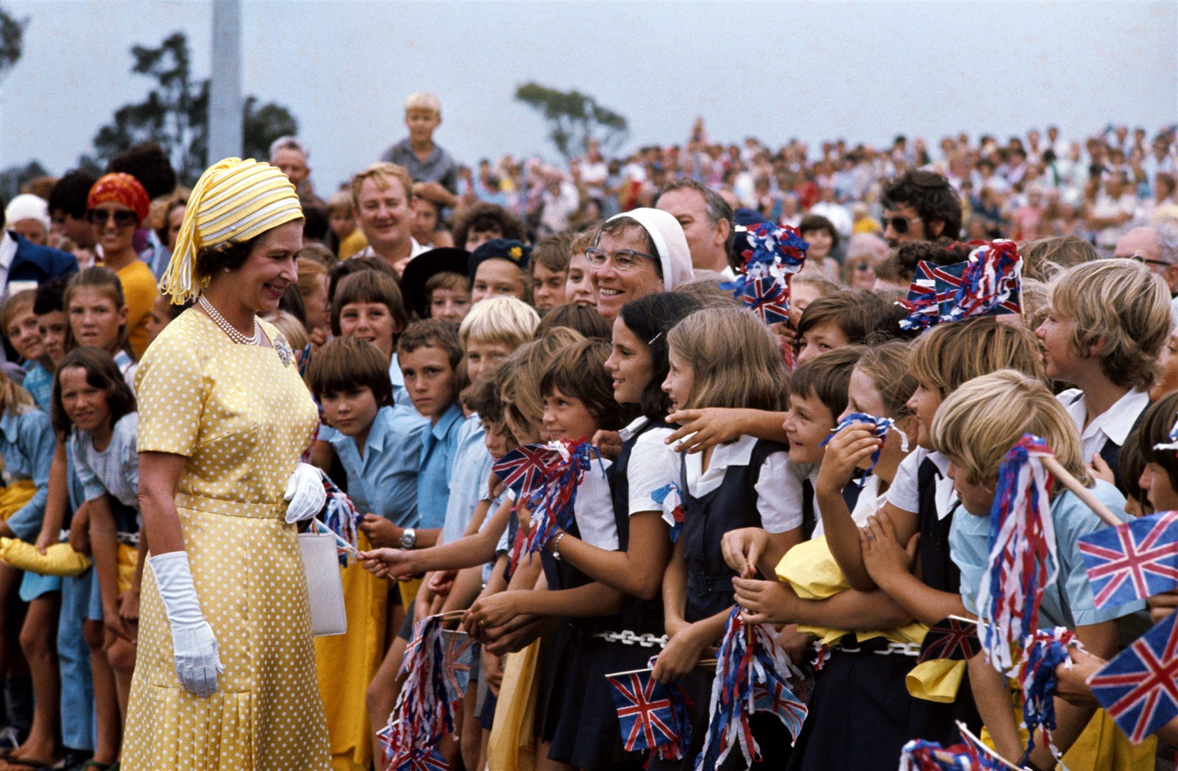 The Queen meets flag-waving school children in Brisbane during her Silver Jubilee Tour of Australia (PA)