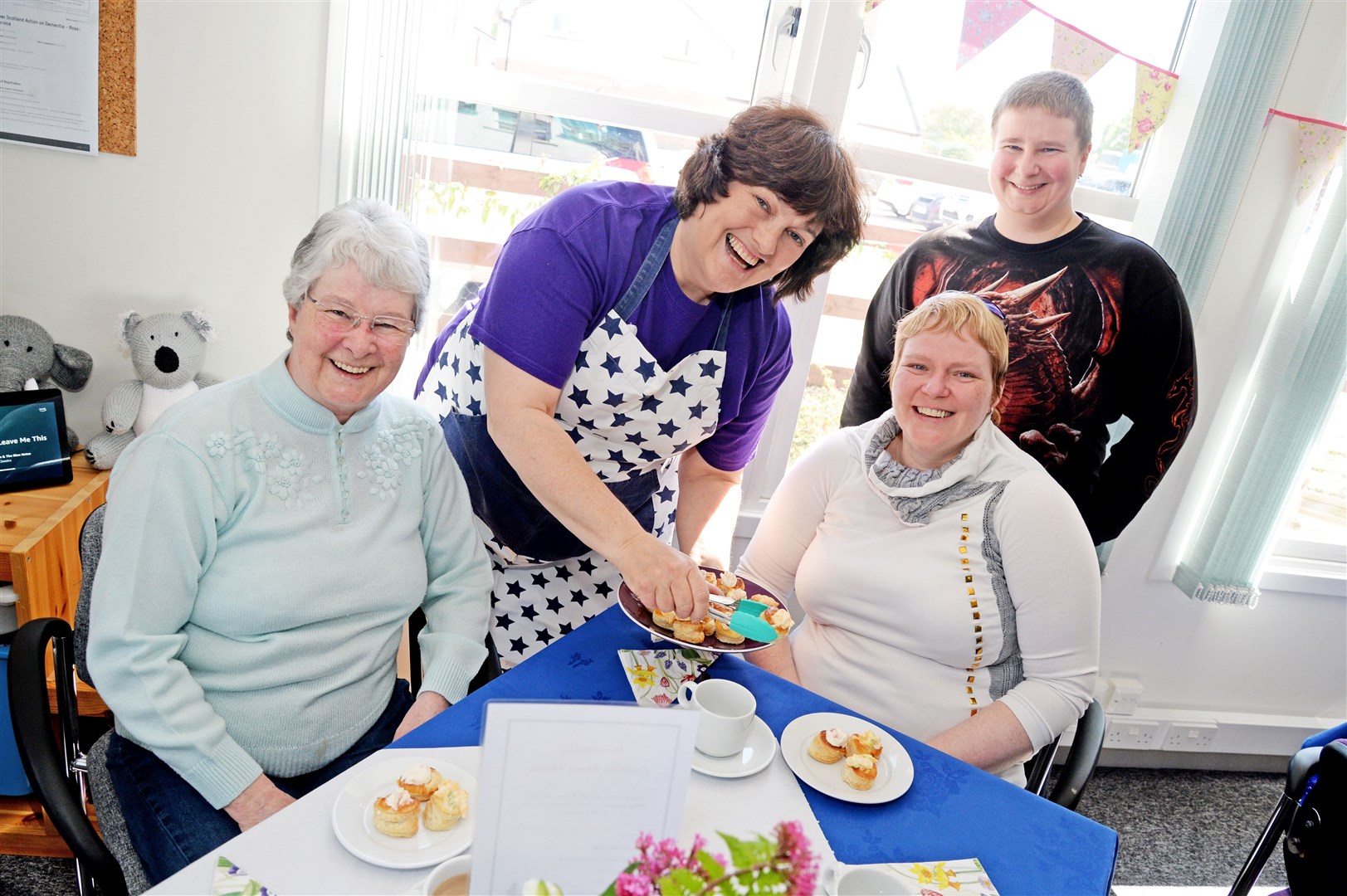 Alzheimer daycare organiser Connie Sinclair dishes out the cakes for Catriona Cowan, Balintore, with her two daughters Tiree Grant (front right), Balintore and Islay Grant, Dingwall. Picture: Gair Fraser. Image No. 044121