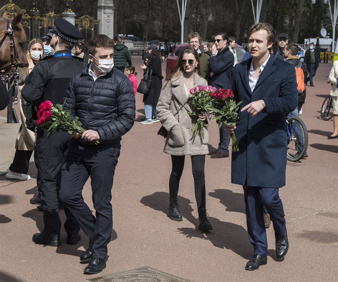 Members of the public carry flowers to leave at the gates of Buckingham Palace (Ian West/PA)